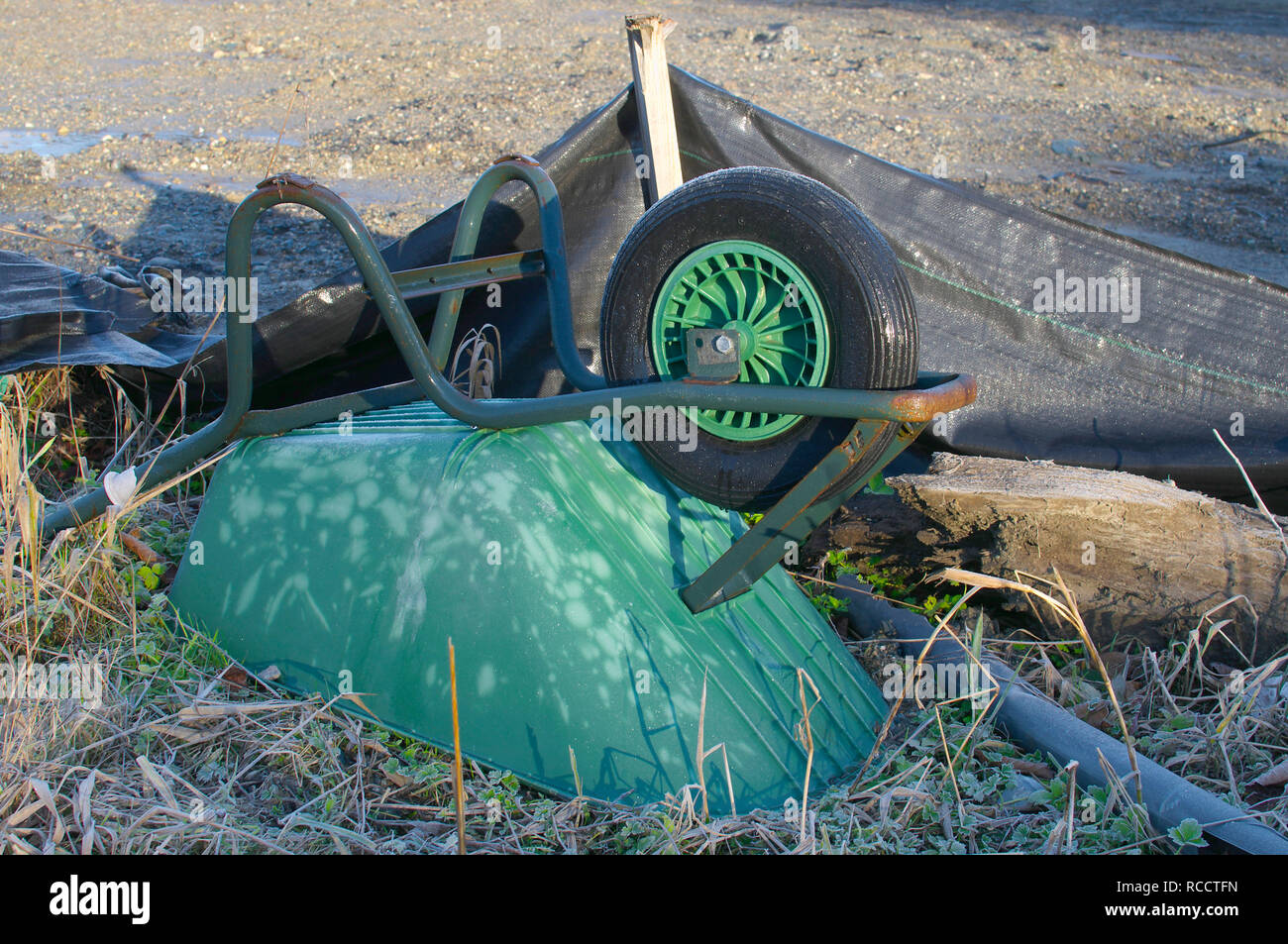 Eine grüne aufgegeben Schubkarre kopfüber in eine leere Baustelle in British Columbia, Kanada. Stockfoto Eine grüne aufgegeben Schubkarre kopfüber in eine leere Baustelle in British Columbia, Kanada. Stockfoto
