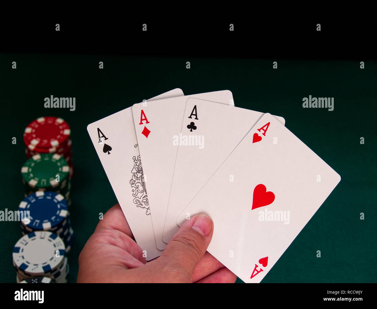 Eine Person spielen Poker mit den vier Asse der ein Deck in der Hand und poker chips in verschiedenen Farben auf der grünen Matte Stockfoto