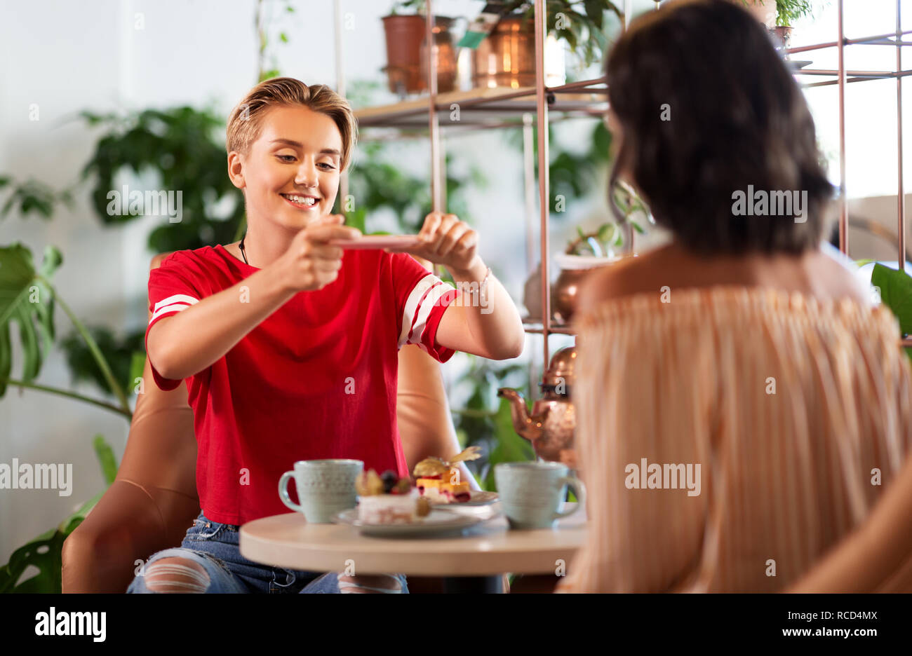 Weibliche Freunde trinken Tee mit Kuchen im Cafe Stockfoto