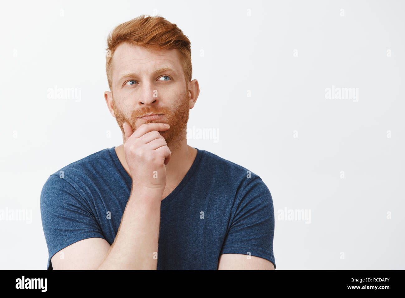 Hmm Wir denken. Portrait von konzentrierte sich kreative und intelligente gut aussehende männliche Stratege mit roten Haaren, stehend in nachdenklicher Pose, reibt Bart und zur Seite schauen beim Denken, bis der Plan im Kopf Stockfoto