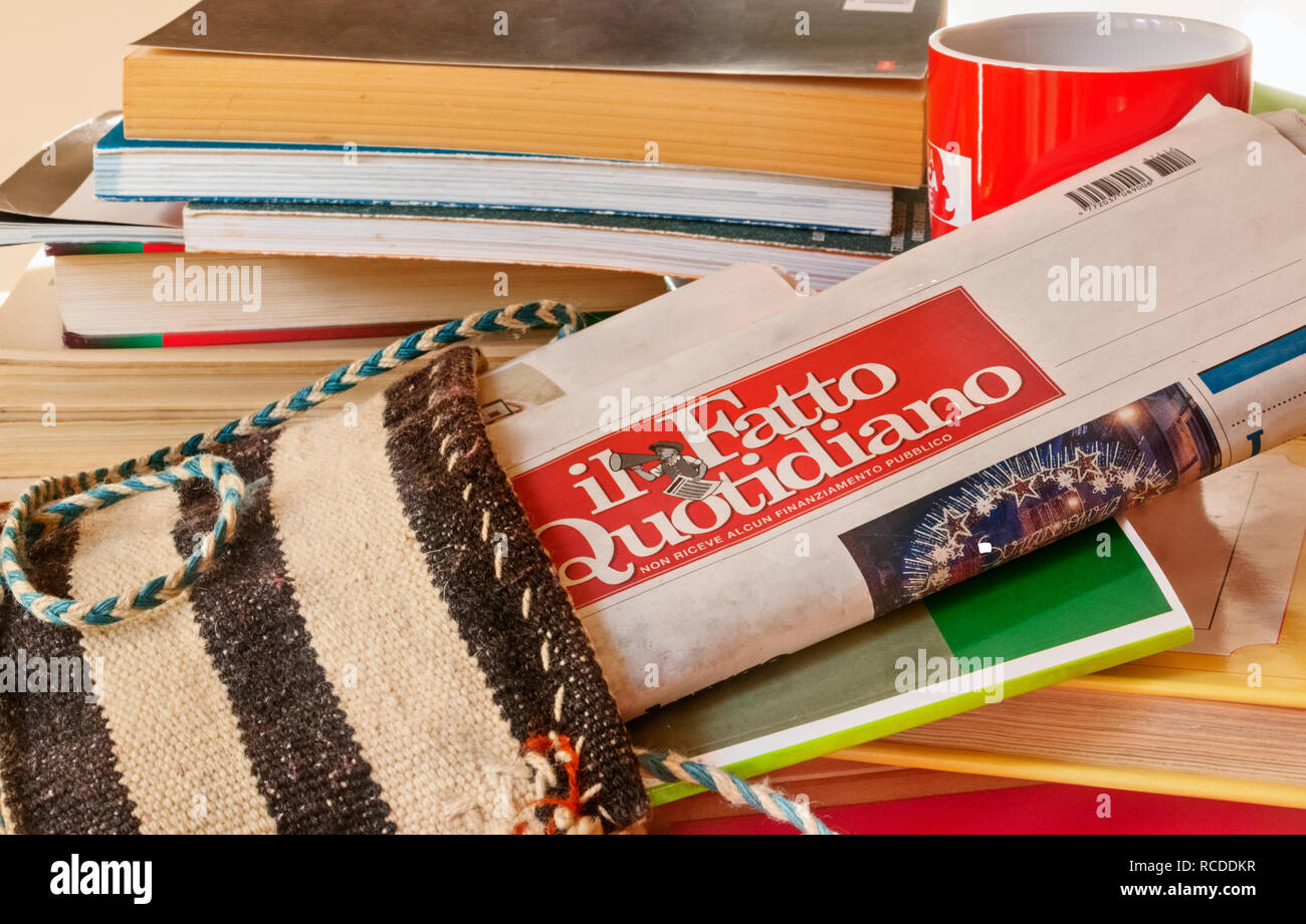 Eine gefaltete Zeitung - il fatto quotidiano - in einem Beutel, einer Gruppe von Bücher und Zeitschrift zwischen dem Journal, eine rote Tasse im Hintergrund Stockfoto