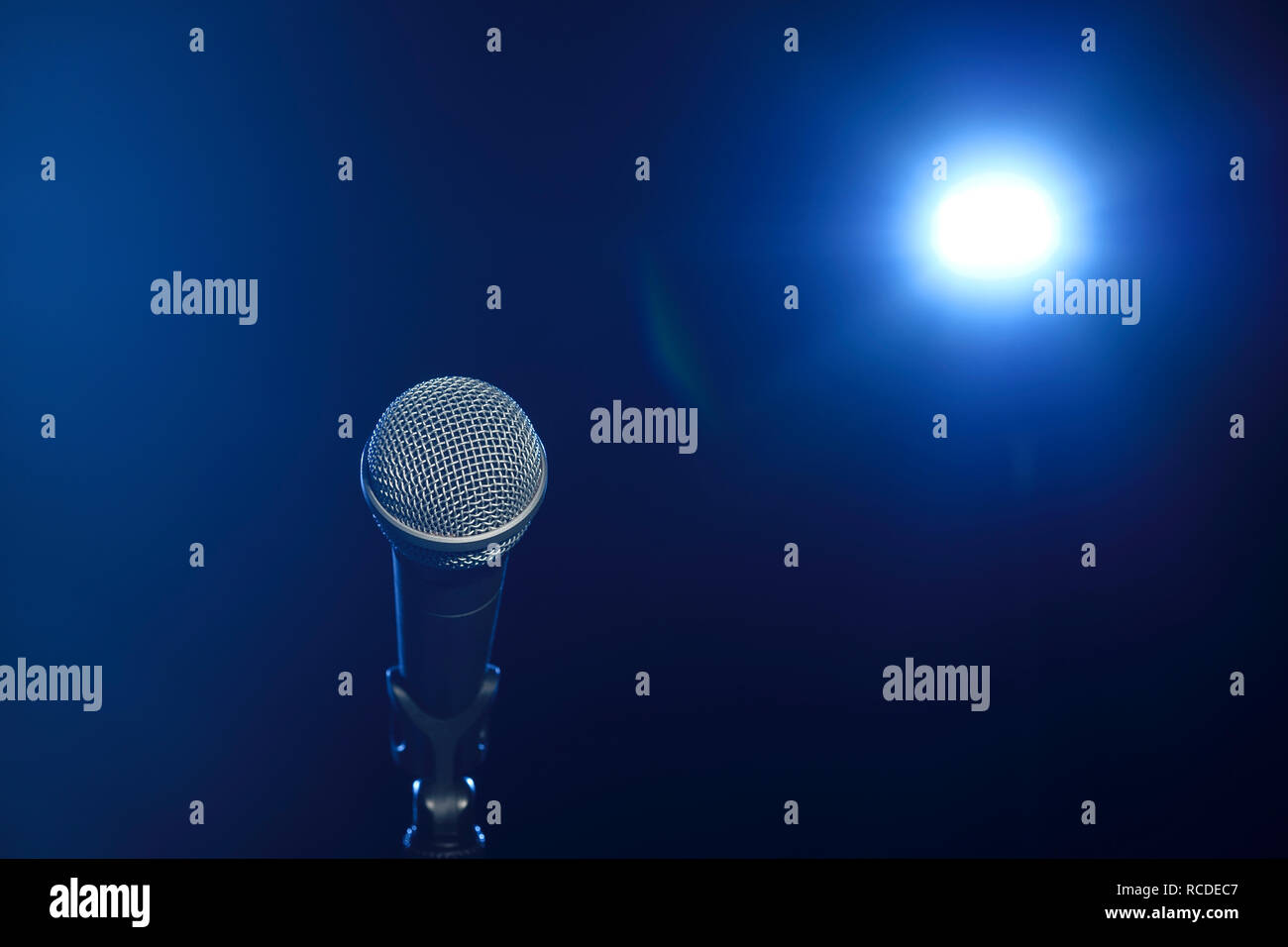 Ein Mikrofon auf der Bühne vor einem Scheinwerfer Stockfoto