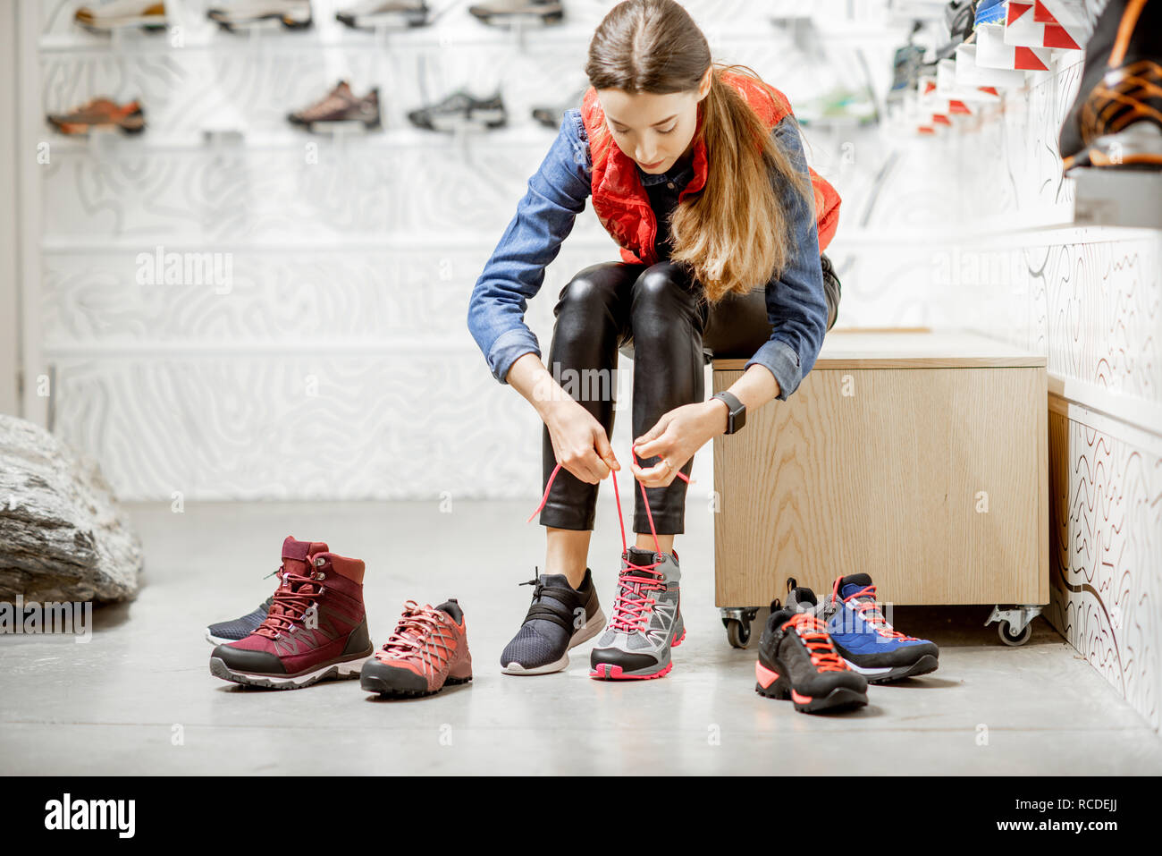 Frau, die versucht, Schuhe für Bergwandern sitzen im Proberaum des modernen Sports Shop Stockfoto