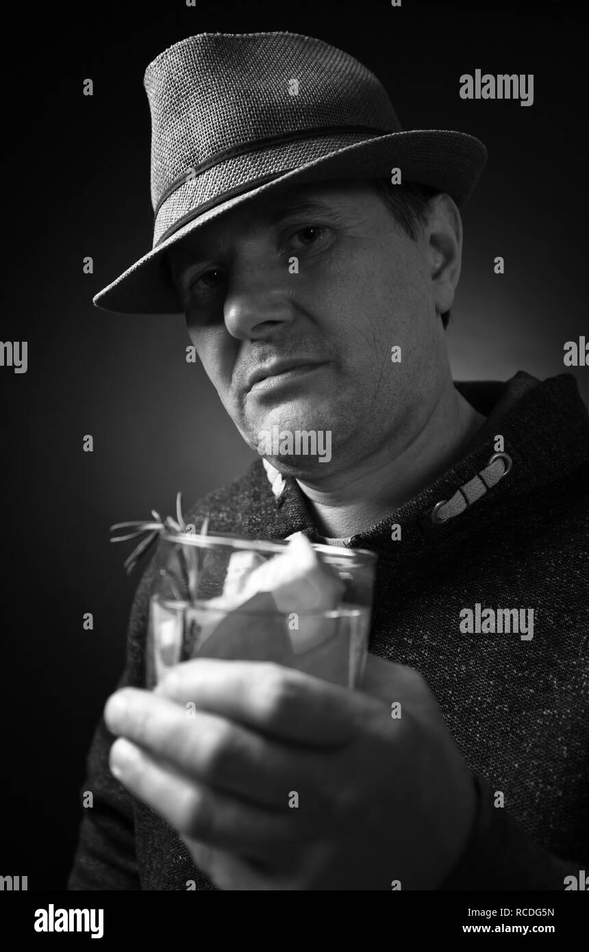 Mann mittleren Alters in einen Hut einen alkoholfreien Cocktail mit Zitrone. Schwarz und Weiß. Stockfoto