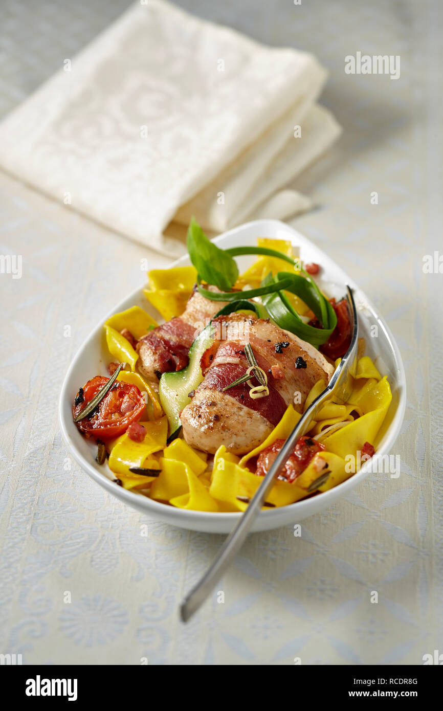 Schweinefilets eingewickelt in Parma Schinken auf Ribbon Nudeln, Tomaten und frischen Kräutern für traditionelle italienische Küche in einer Schüssel mit Kopie Raum über Stockfoto