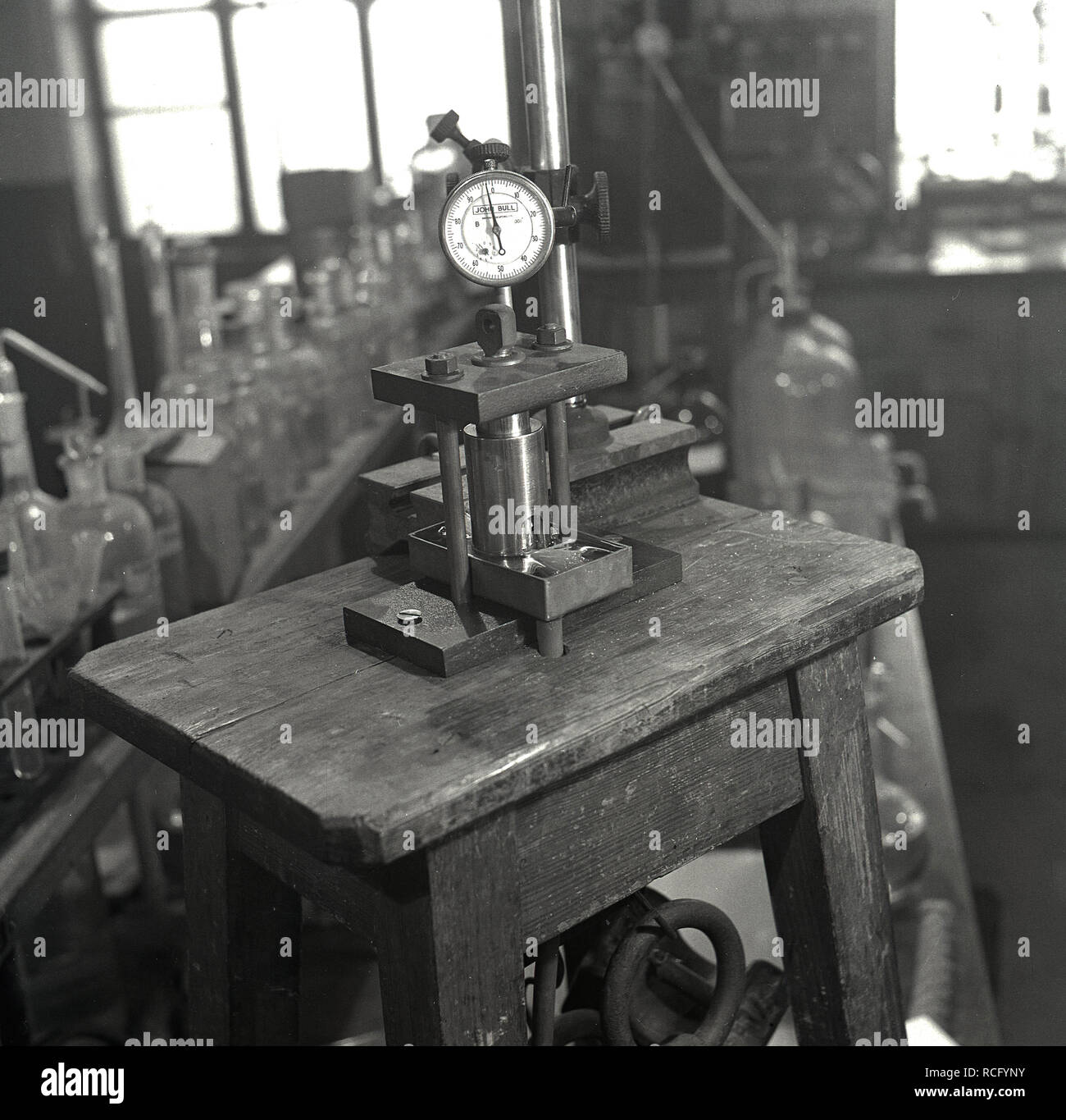 1950s, historisch, ein wissenschaftliches Labor, auf einer kleinen hölzernen Werkbank, einem „John Bull“-Instrument, einem auf dem Tisch befestigten Messuhr, Leeds University, Leeds, England, Großbritannien. Die „John Bull“-Testgeräte der Ära wurden von British Indicators Ltd aus Pickford Rd, St Albans, England, Großbritannien, hergestellt, einem führenden Hersteller von Präzisions-internen Mess- und Messgeräten. Stockfoto