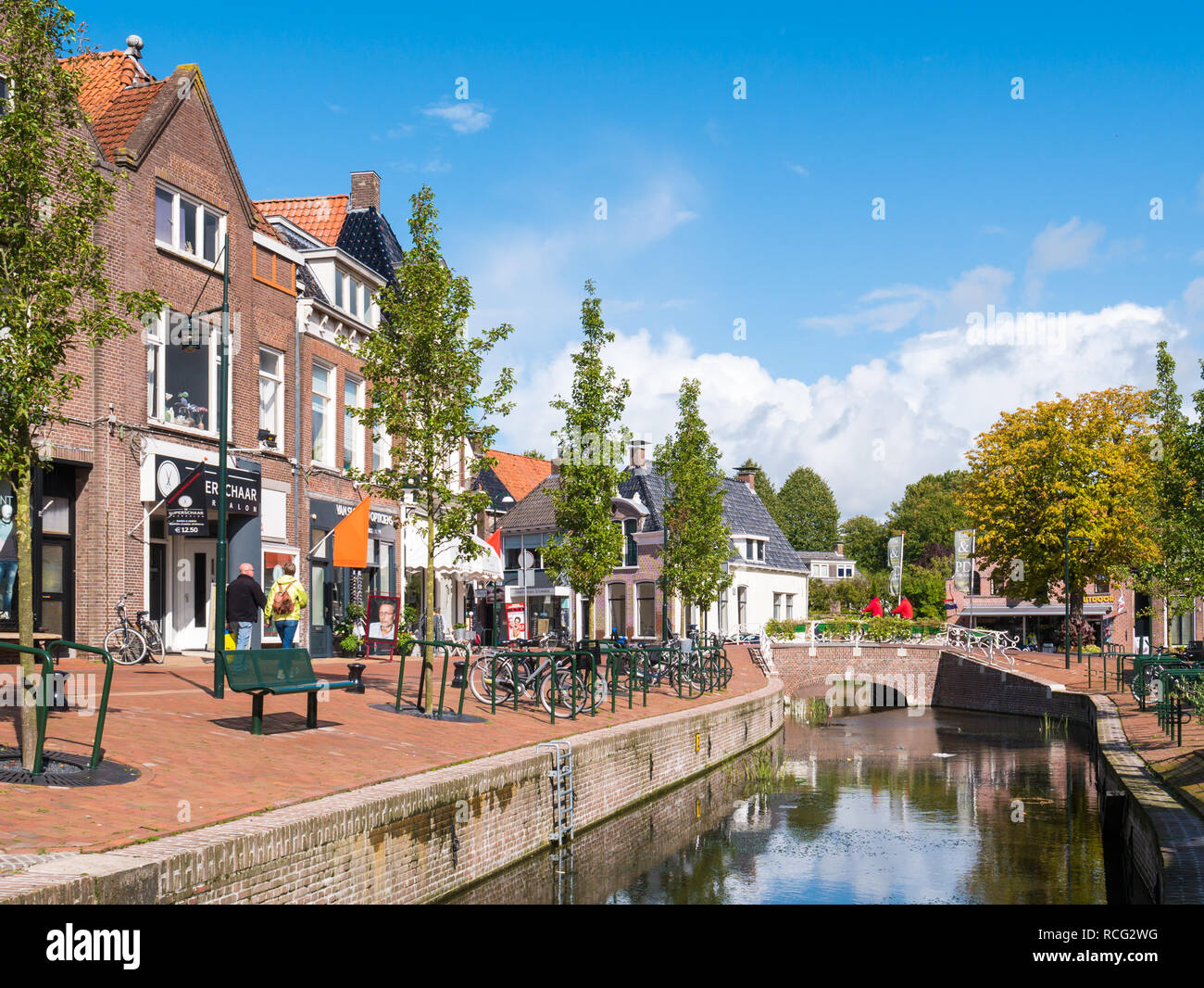 Menschen zu Fuß auf Kai mit Geschäften und Kanal in der Altstadt von Dokkum, Friesland, Niederlande Stockfoto
