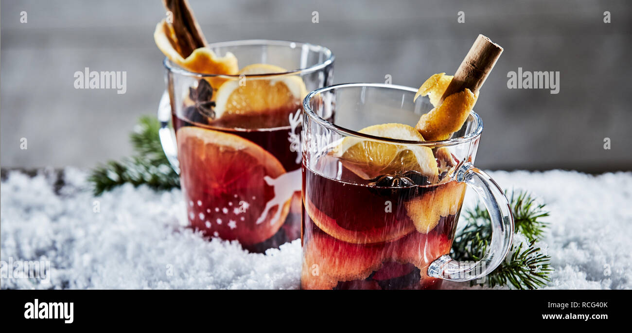 Panorama Banner mit zwei Gläser Weihnachten Glühwein oder Glühwein Rotwein garniert mit Stick Zimt und im Winter Schnee mit Kopie Raum serviert. Stockfoto