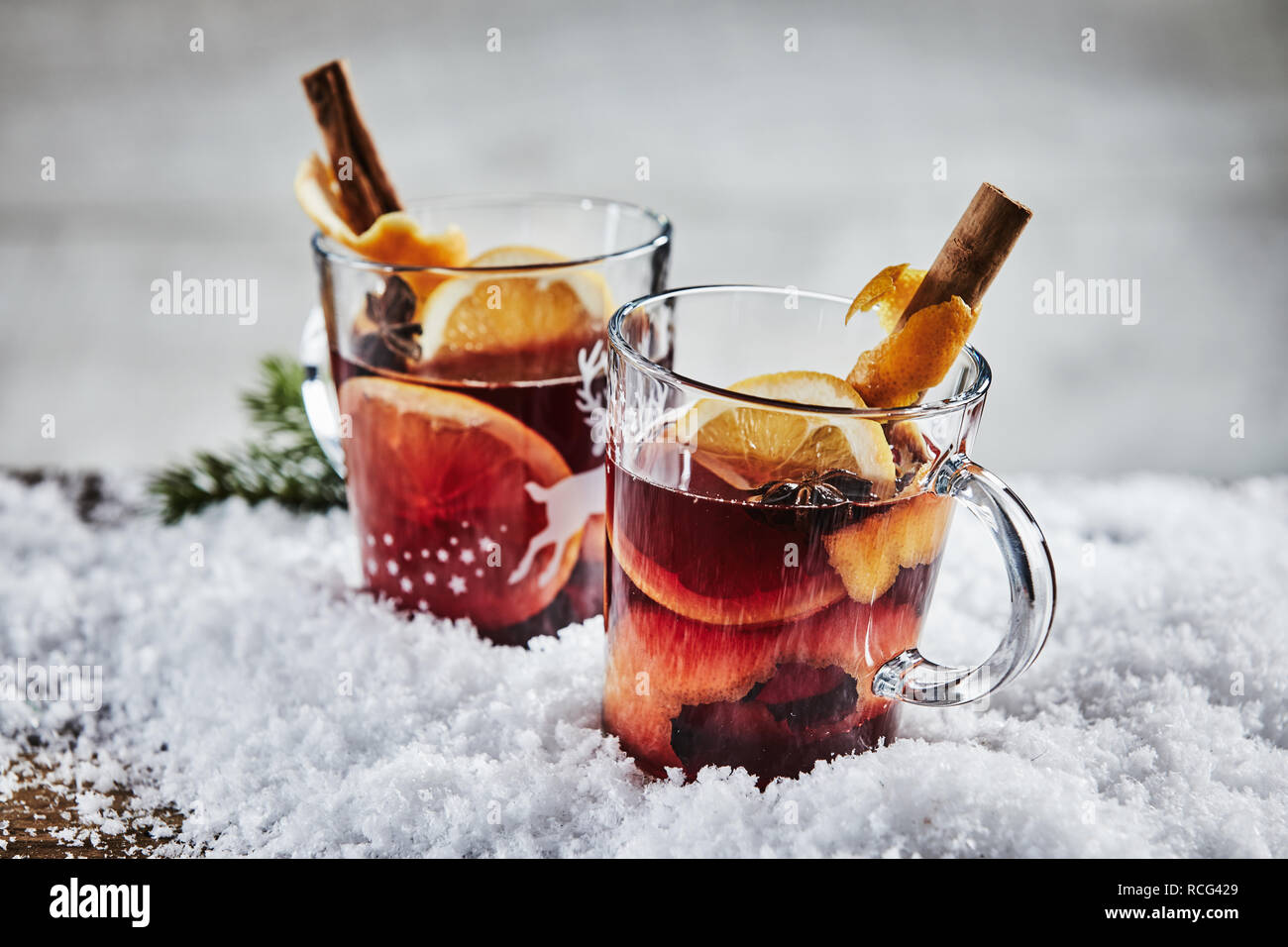 Traditionelle Hot würzigen Glühwein Glühwein oder Rotwein für Weihnachten mit Orangen, Zimt und Sternanis in zwei Glas Becher im Winter Schnee serviert. Stockfoto