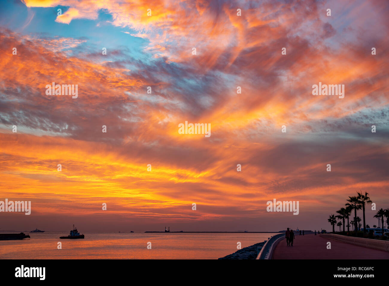 Silhouetten, die auf der Palm Jumeirah boardwalk bei Sonnenuntergang in Dubai, Vereinigte Arabische Emirate Stockfoto