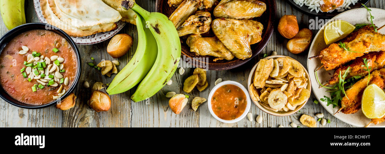 West African food Konzept. Traditionelle Wset afrikanische Gerichte Sortiment - peanut Soup, jollof Reis, gegrillte Chicken Wings, chemische gebratene Bananen Bananen, Stockfoto