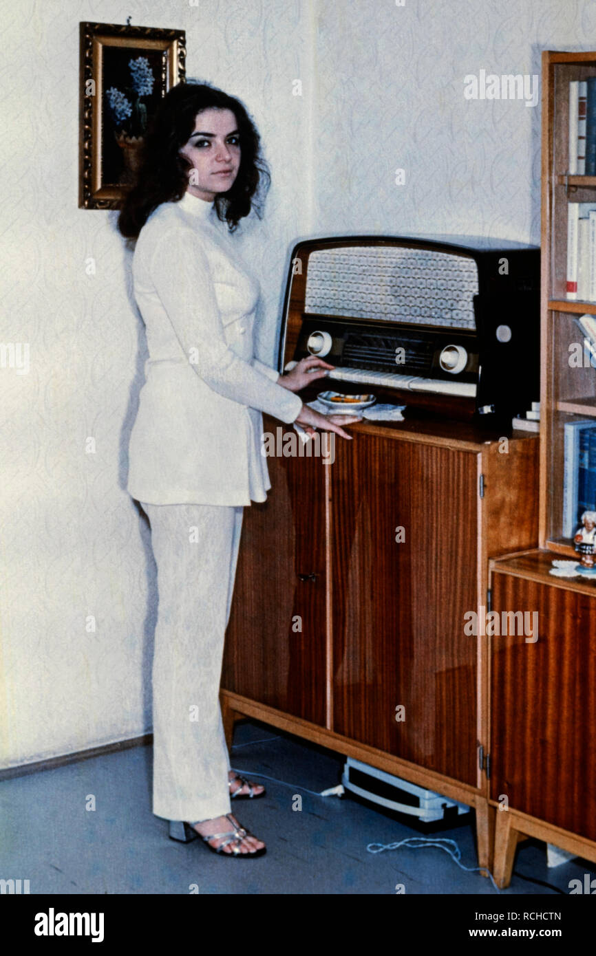Junge hübsche Brünette Frauen Tragen eines weißen Hosenanzug neben Vintage Radio set 70er Ungarn Stockfoto
