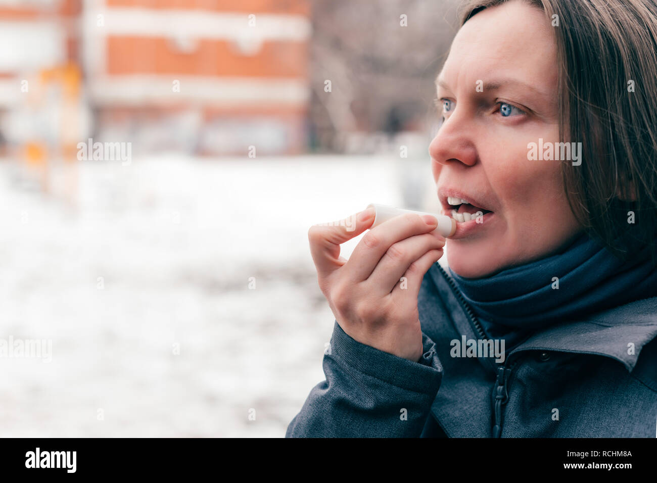 Frau Anwendung Lip Balm auf der Straße an einem kalten Wintertag Stockfoto