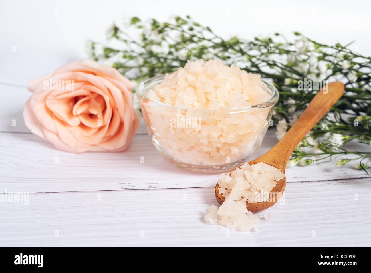 Natürliche Hautpflege Konzept. Organische Kosmetik mit rosa Salz Spa in Glas und Holz Schüssel Löffel dekorieren mit rosa und weiße Blume Stockfoto