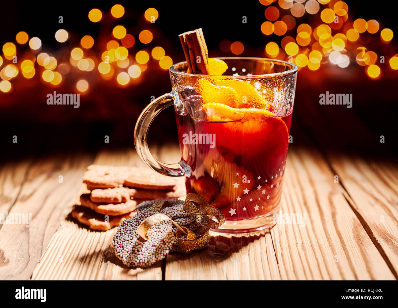 Glas heissem würzigen Glühwein mit Cookies auf einem Holztisch mit einer Kulisse der funkelnden Weihnachtsfeier leuchtet Stockfoto