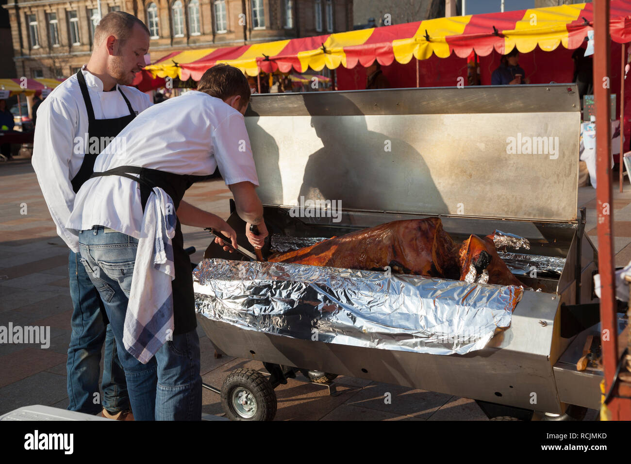 Zwei Köche am Schwein braten am Bauernmarkt, Helensburgh, Schottland Stockfoto