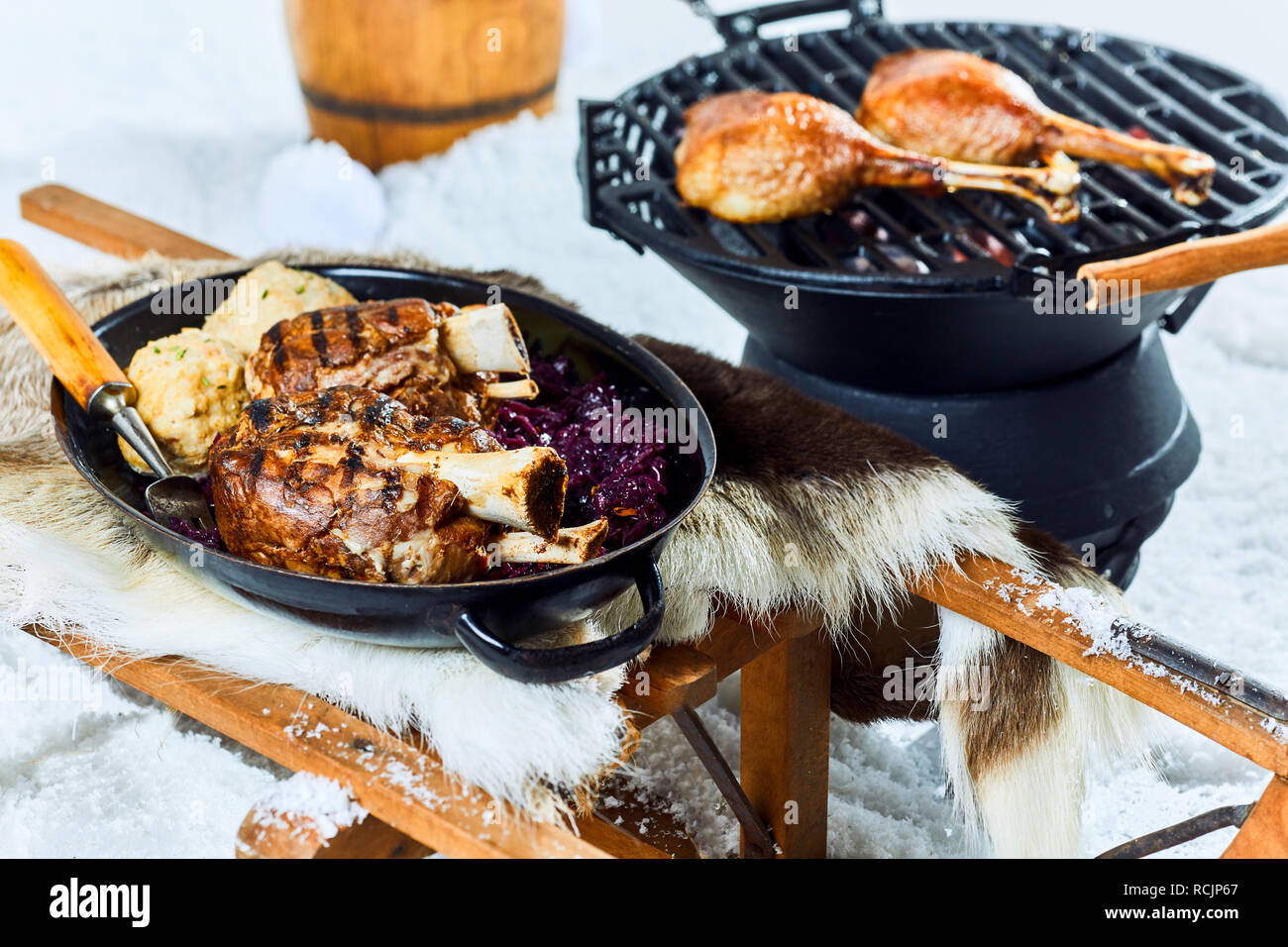 Gesundes Schweinefleisch vom Grill Sprunggelenk mit Knödel aus einem Winter Barbecue mit Rotkohl in einem Topf auf einem Bett von frischem Schnee serviert. Stockfoto