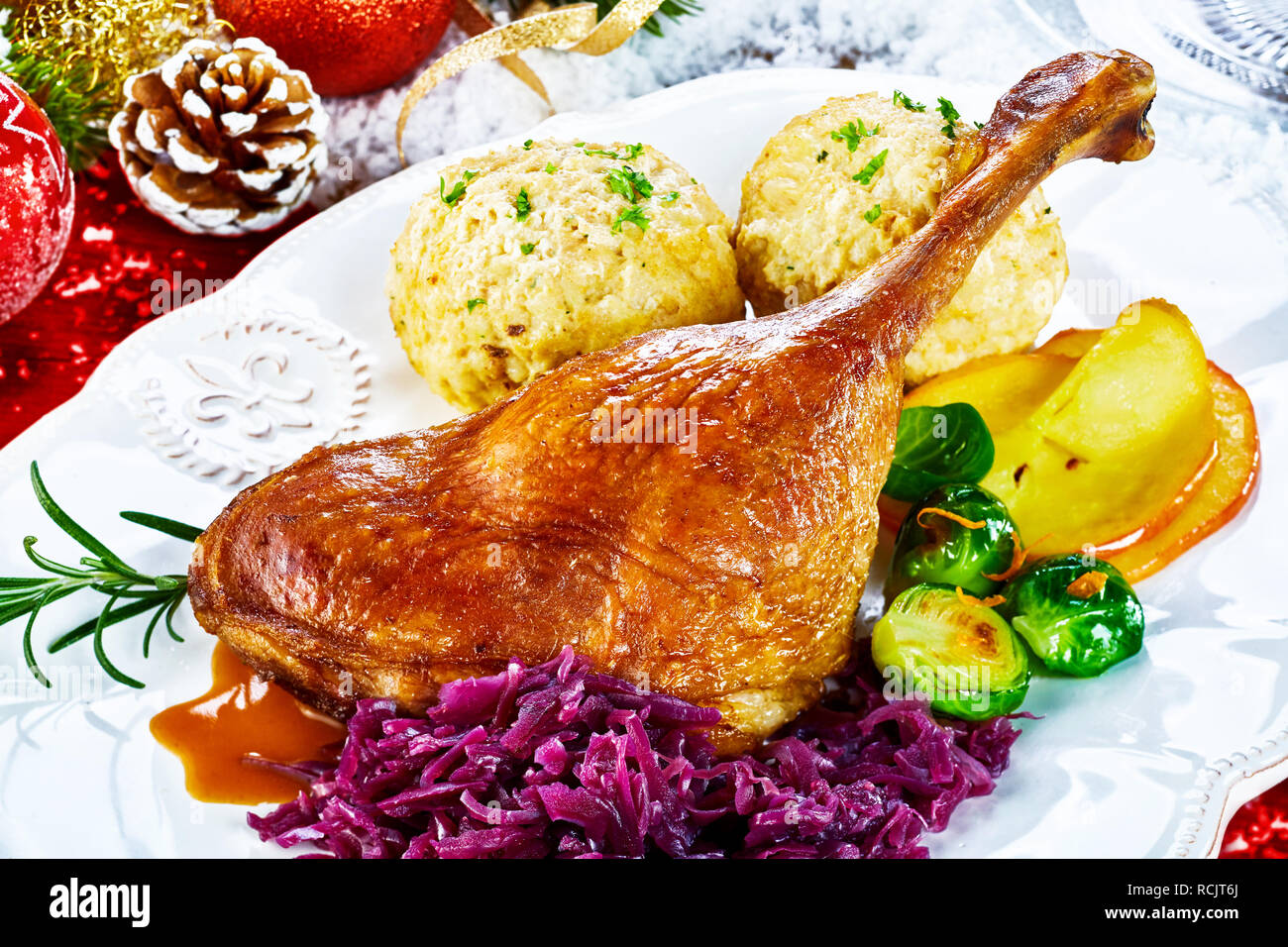 Knusprige golden gebratene Weihnachten Türkei Bein mit frischem Gemüse und Knödel serviert auf einem Tisch mit Weihnachten Dekorationen in der Nähe zu sehen, einstellen Stockfoto