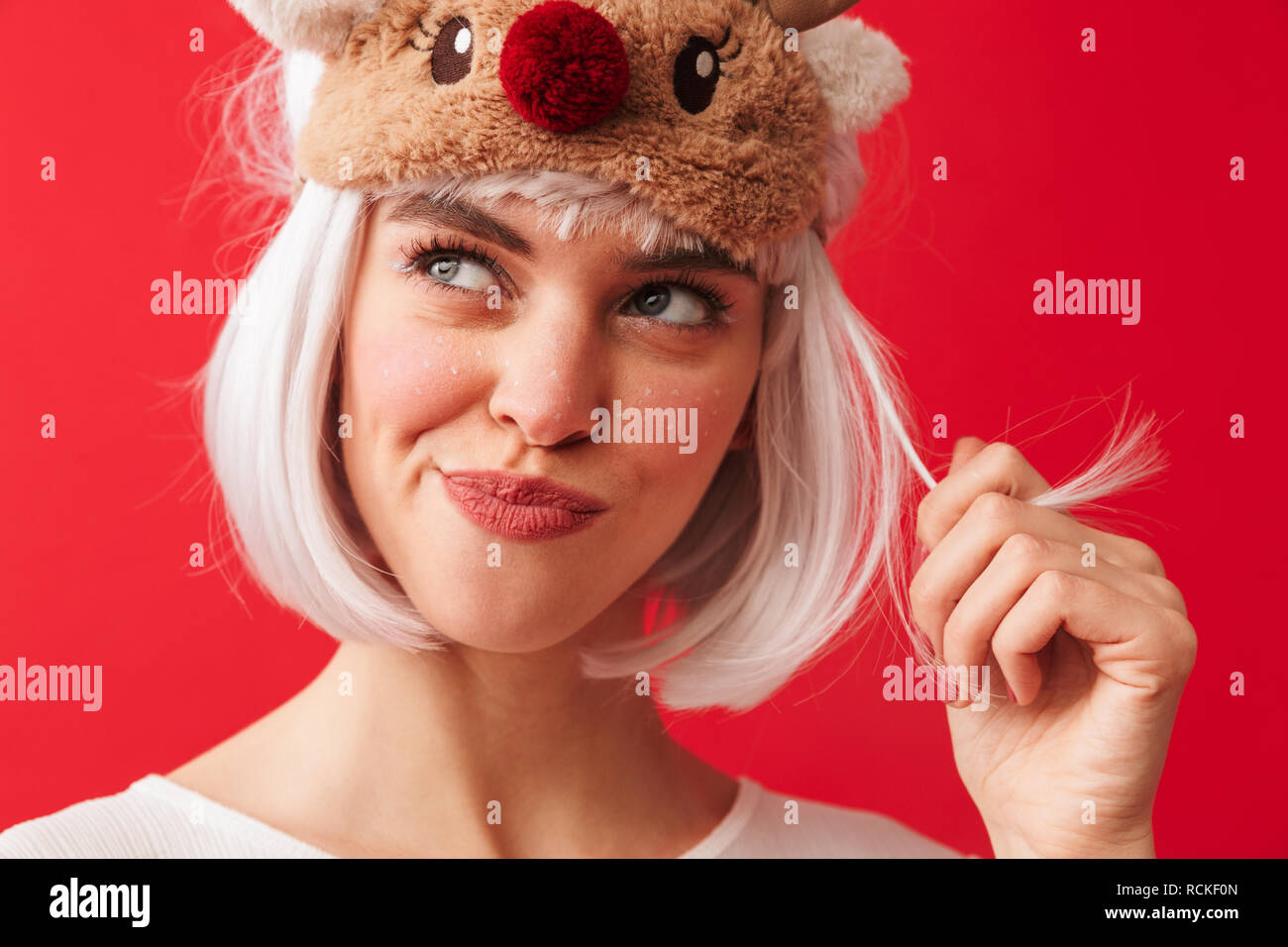 Bild einer jungen schönen Frau in Karneval Weihnachten kostüm über rote Wand Hintergrund spielen mit Haar isoliert Posing gekleidet. Stockfoto