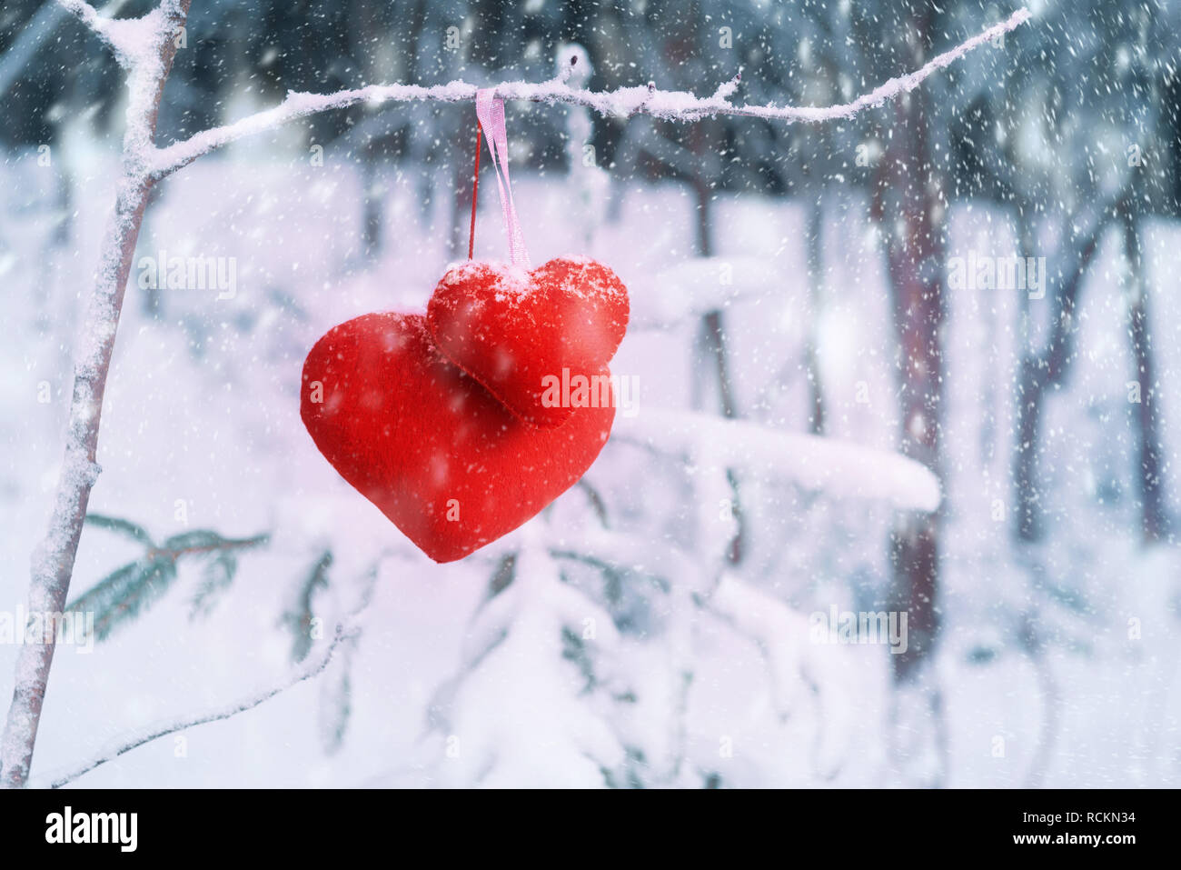 Zwei rote Stoff Herz auf schneebedeckten Ast. Valentinstag Konzept Stockfoto