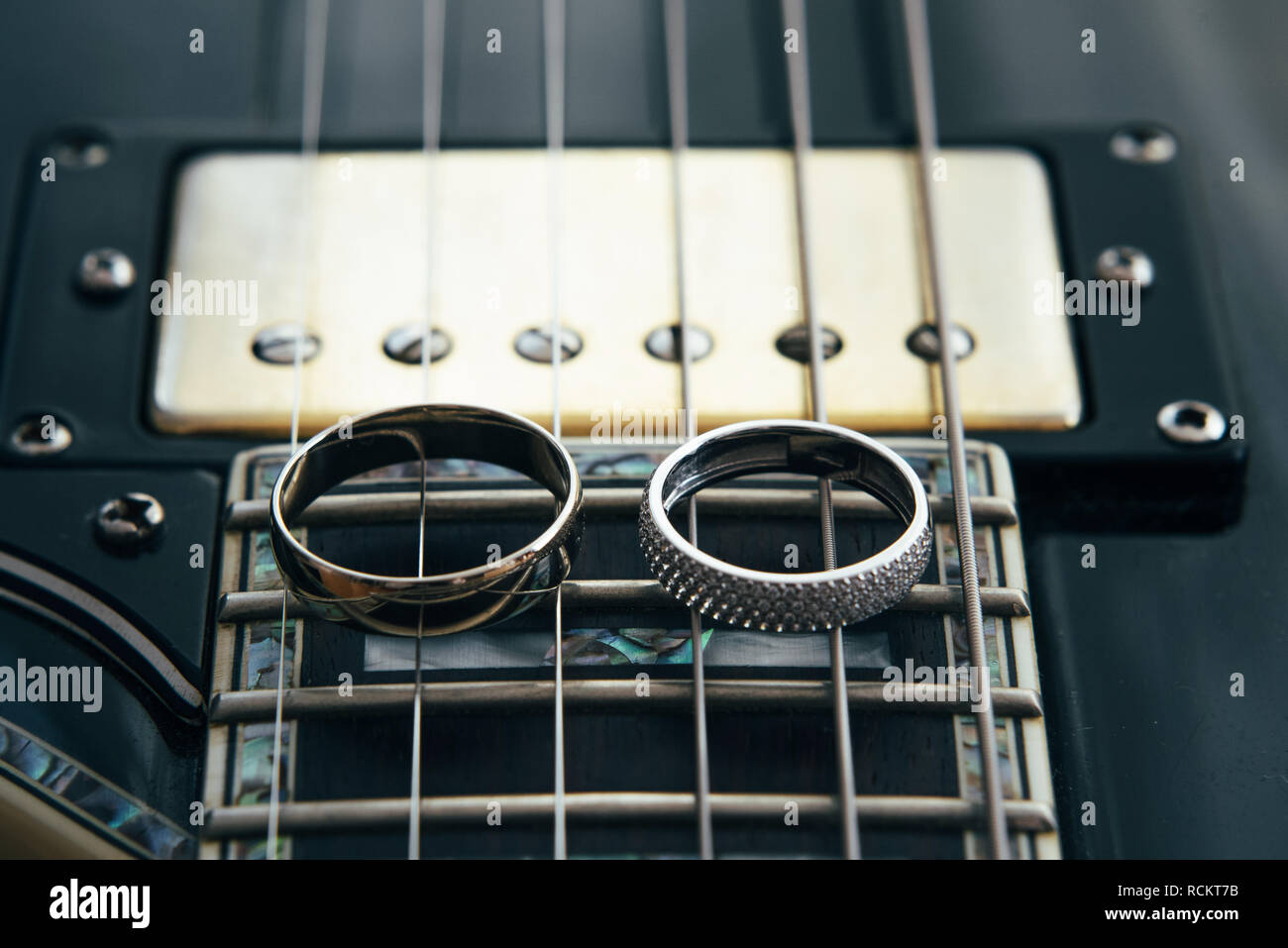 Trauringe auf die Saiten der Gitarre Stockfoto