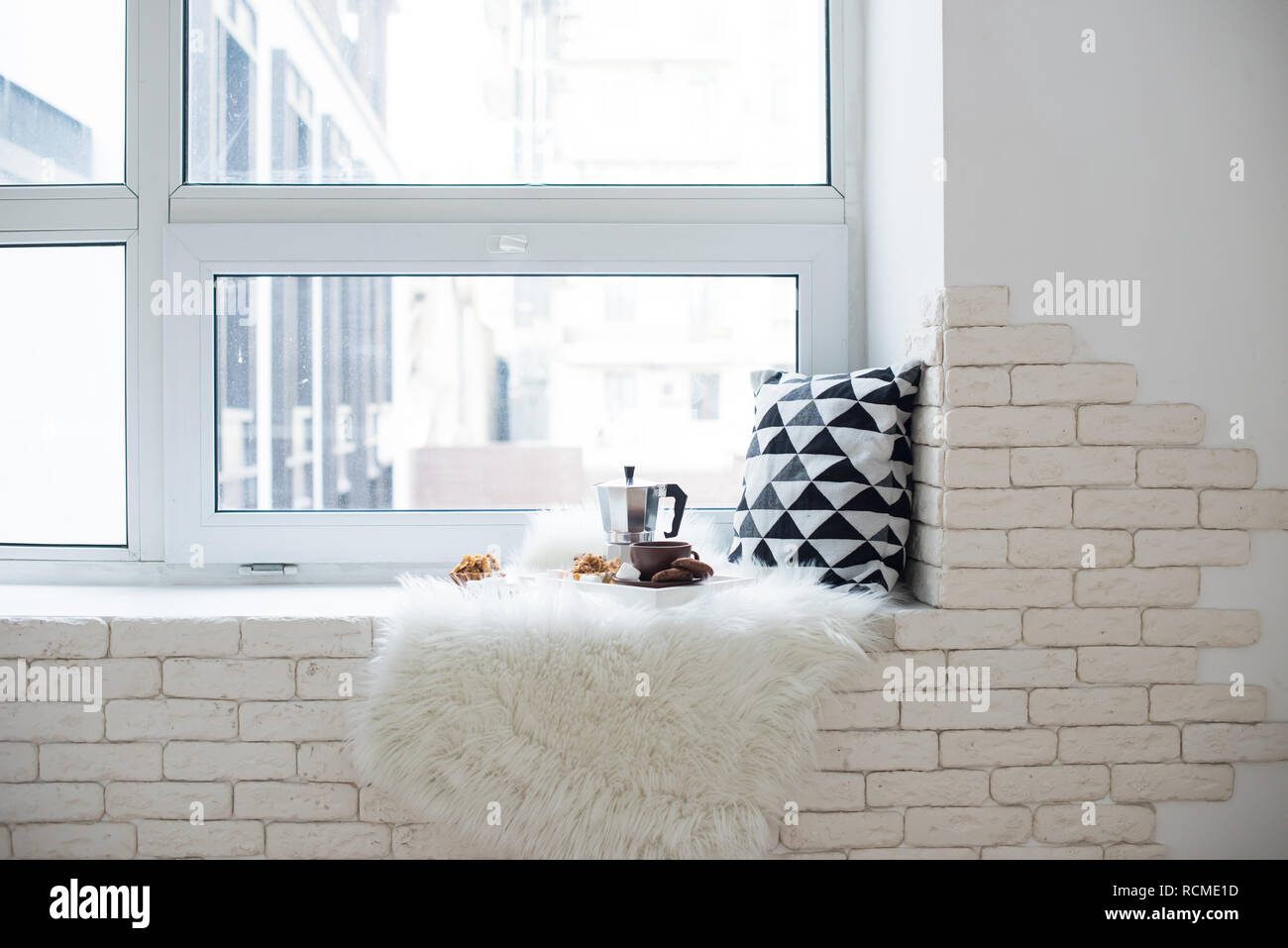 Gemütliche winter home Anordnung auf der Fensterbank, Kaffee und Cookies auf Fach mit Kissen und Fellimitat weiße Decke Stockfoto