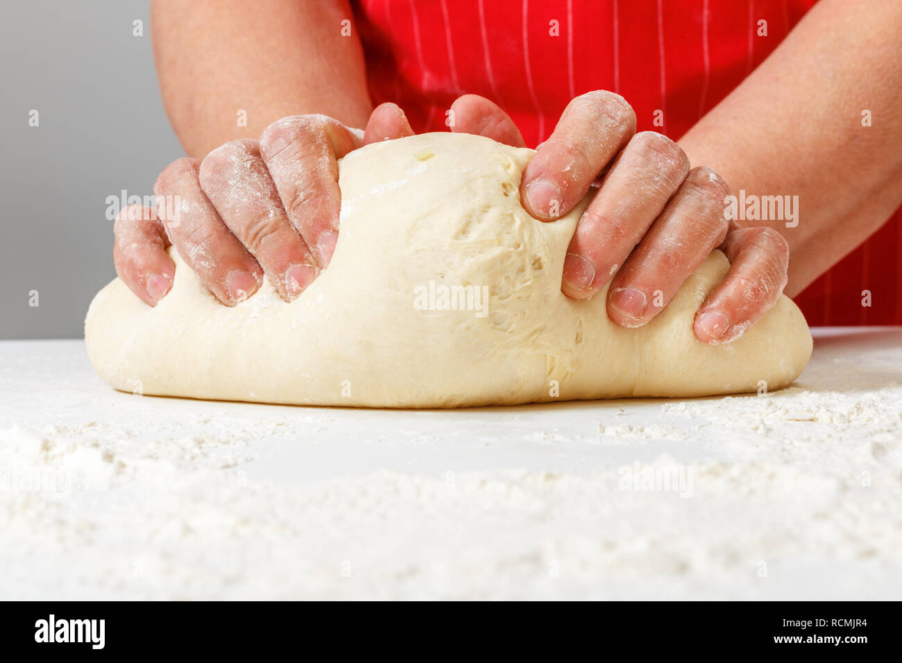 Ältere Frau rohe frische knetet Teig mit den Händen auf den Tisch. Stockfoto