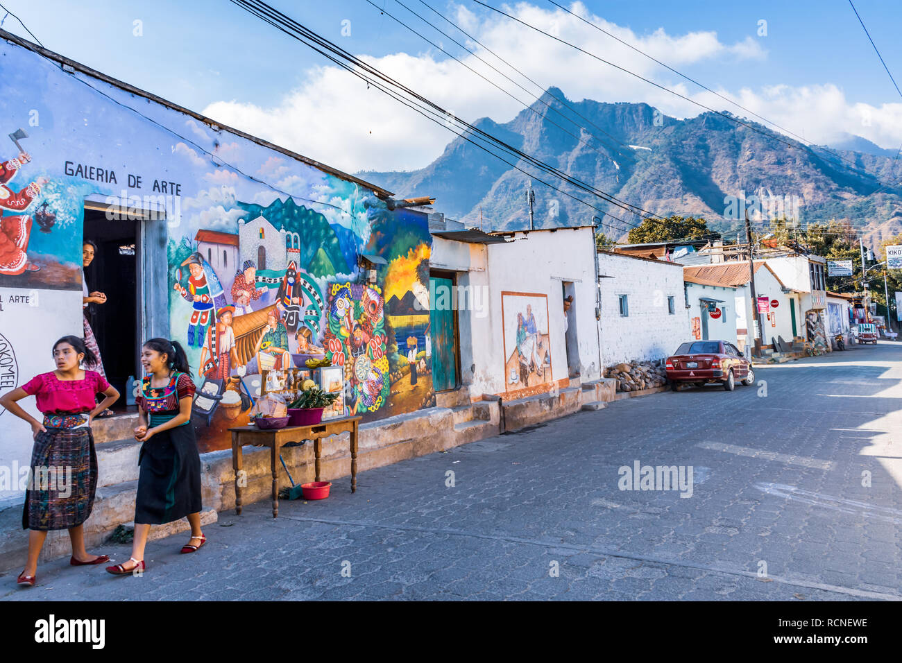 San Juan La Laguna, Atitlan See, Guatemala - Dezember 31, 2018: Maya Frauen in traditioneller Kleidung, Straße Wandbild und Indische Nase Nationalpark hinter sich. Stockfoto