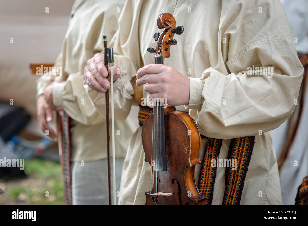 Riga. Lettland. Ein Mann in Tracht hält eine Geige in der Hand. Stockfoto