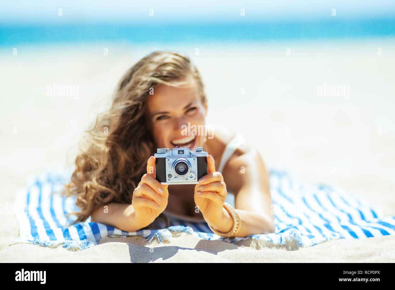 Nahaufnahme auf retro Foto Kamera Holding durch Frau Festlegung auf ein gestreiftes Handtuch auf der Seeküste. Erfassen Urlaub in unglaubliche Fotos die Guten zu erleben, t Stockfoto Nahaufnahme auf retro Foto Kamera Holding durch Frau Festlegung auf ein gestreiftes Handtuch auf der Seeküste. Erfassen Urlaub in unglaubliche Fotos die Guten zu erleben, t Stockfoto