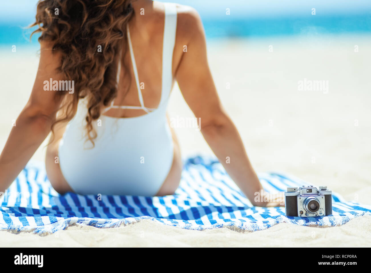 Nahaufnahme auf retro Foto Kamera und Frau sitzt auf einem gestreiften Handtuch auf der Seeküste. Erfassen Urlaubsfotos zu Erinnerungen oder Teilen Beach Vacati bewahren Stockfoto Nahaufnahme auf retro Foto Kamera und Frau sitzt auf einem gestreiften Handtuch auf der Seeküste. Erfassen Urlaubsfotos zu Erinnerungen oder Teilen Beach Vacati bewahren Stockfoto