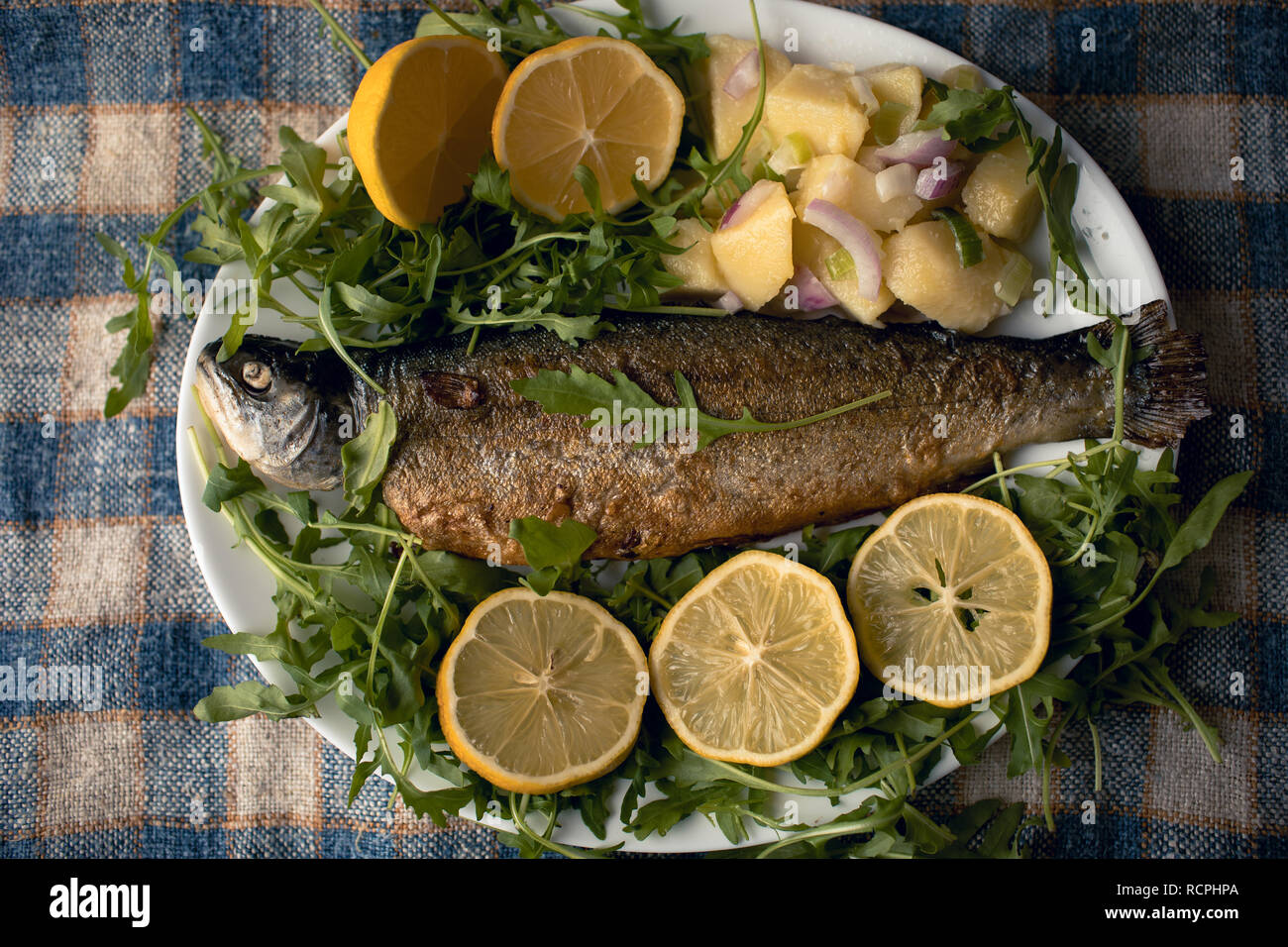 Gegrillter Fisch auf dem Teller mit Zitrone und Salat serviert. Stockfoto
