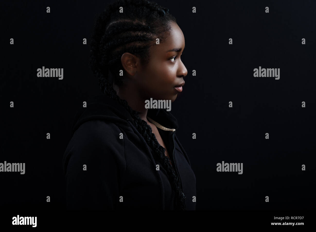 Cool und schön schwarz Female Model weg schauen auf schwarzem Hintergrund Stockfoto