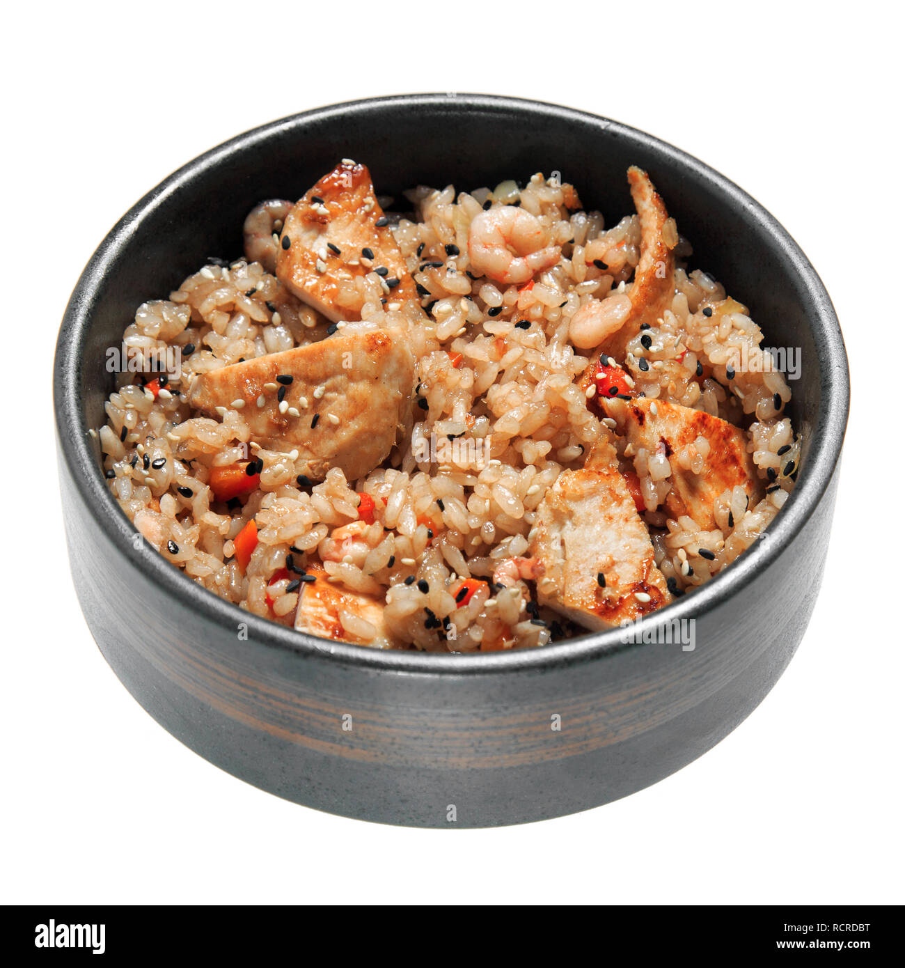 Reis mit gebratenes Huhn, Garnelen, Gemüse und Sesam im schwarzen Schüssel. Auf weissem Hintergrund. Leckeres Restaurant Dish. Stockfoto