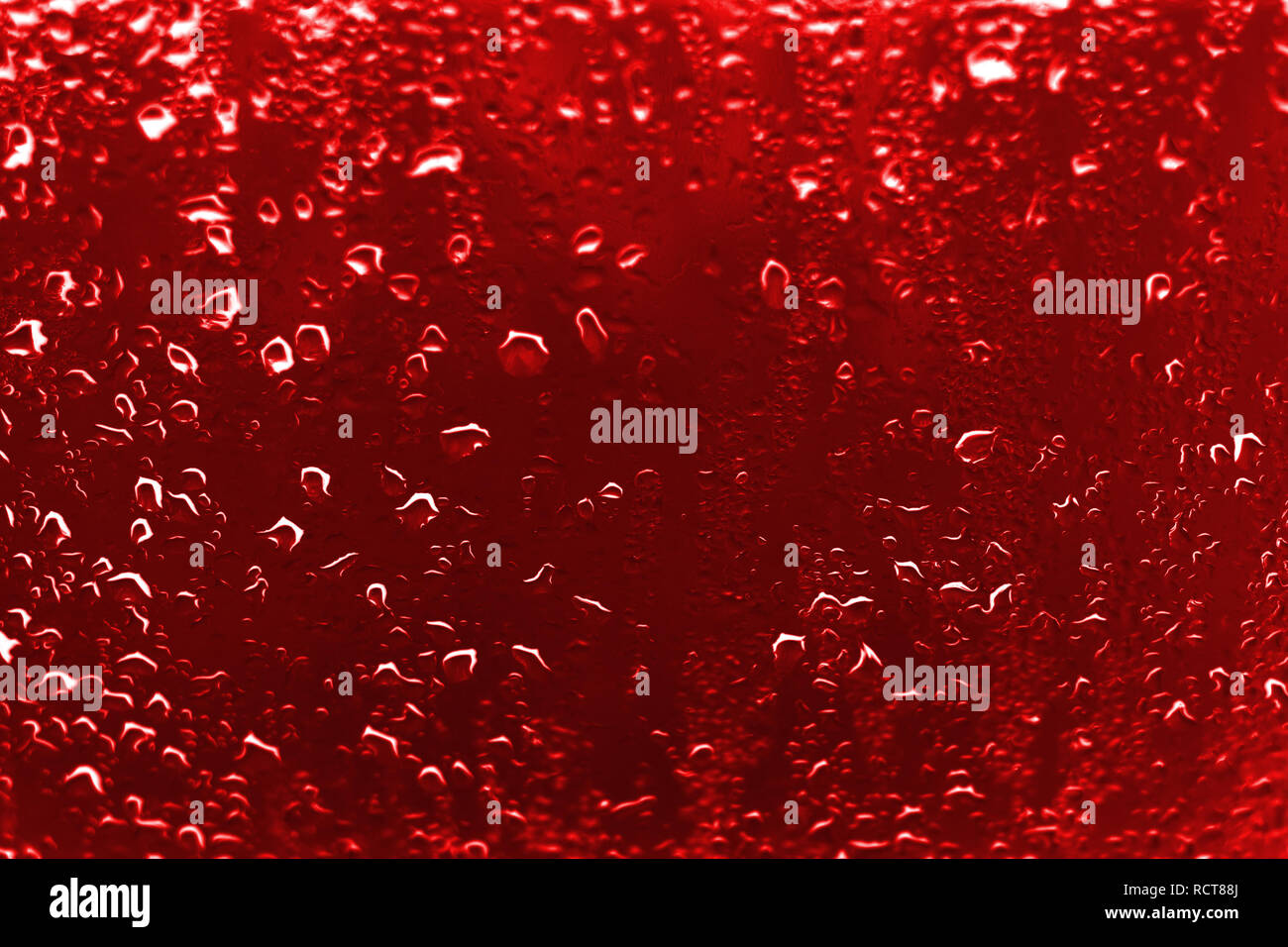 Hoher Kontrast Foto von Regentropfen auf einem Fenster Glas mit leuchtend roter scharlachrote Farbe Stockfoto
