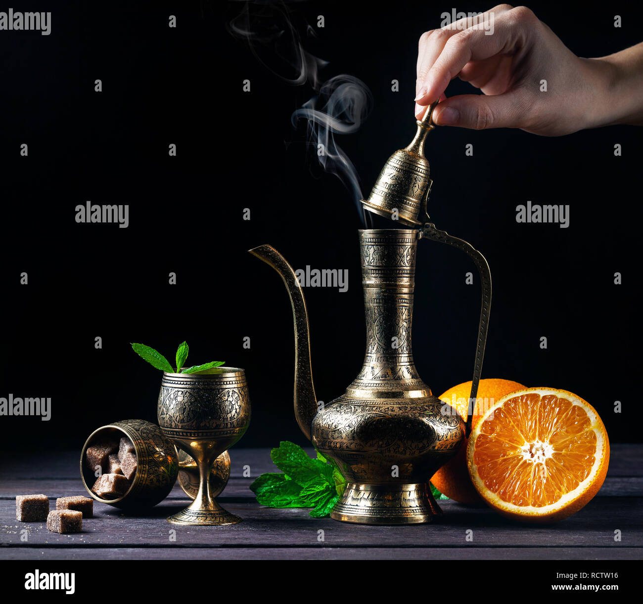 Marokkanischen Tee mit Minze und Orangen in orientalischen Cooper pot und Tassen auf rustikalen Holzmöbeln Hintergrund Stockfoto