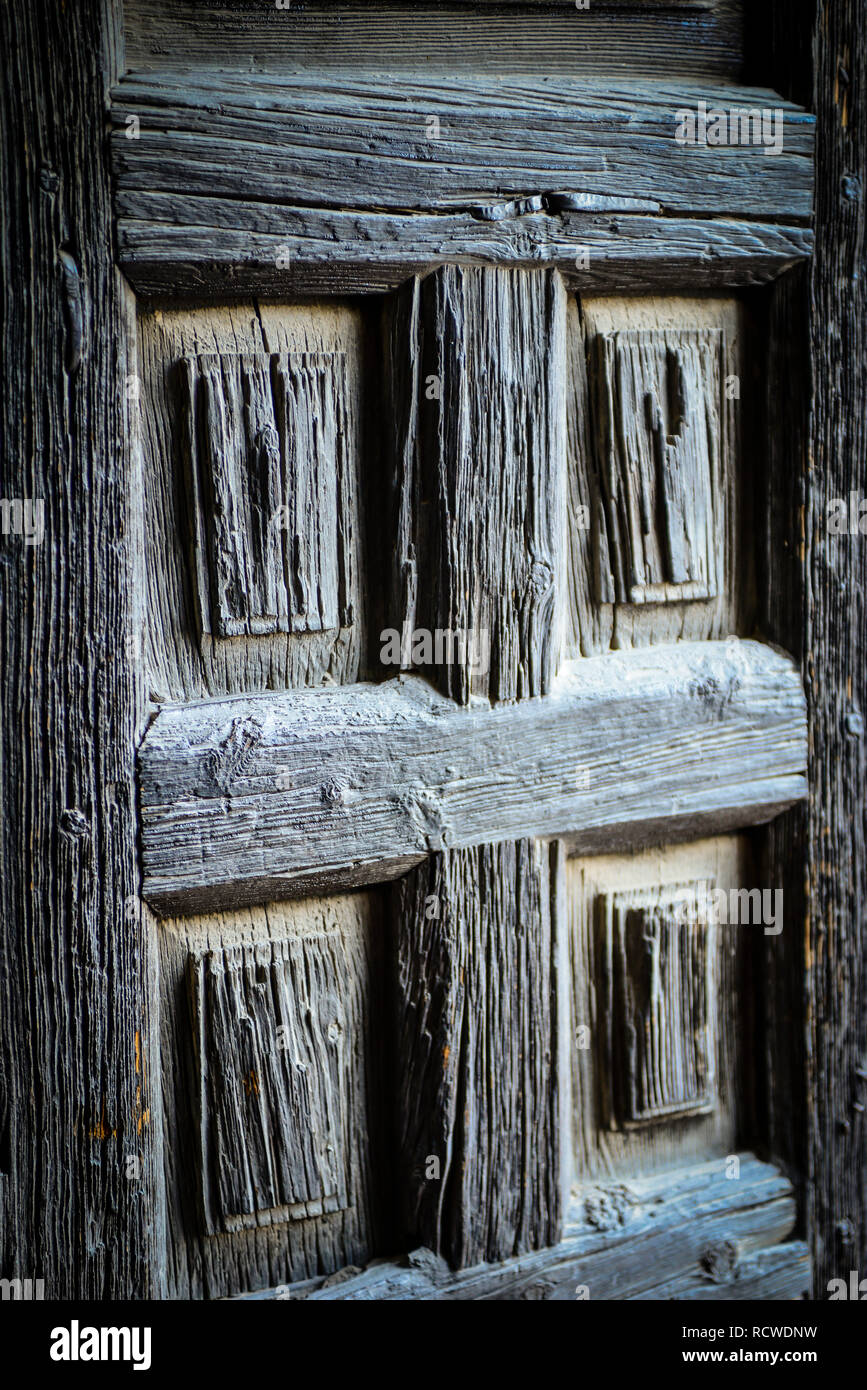 Nahaufnahme einer alten und verwitterten alten, staubigen, abgenutzten, handgeschnitzten Holztür Stockfoto