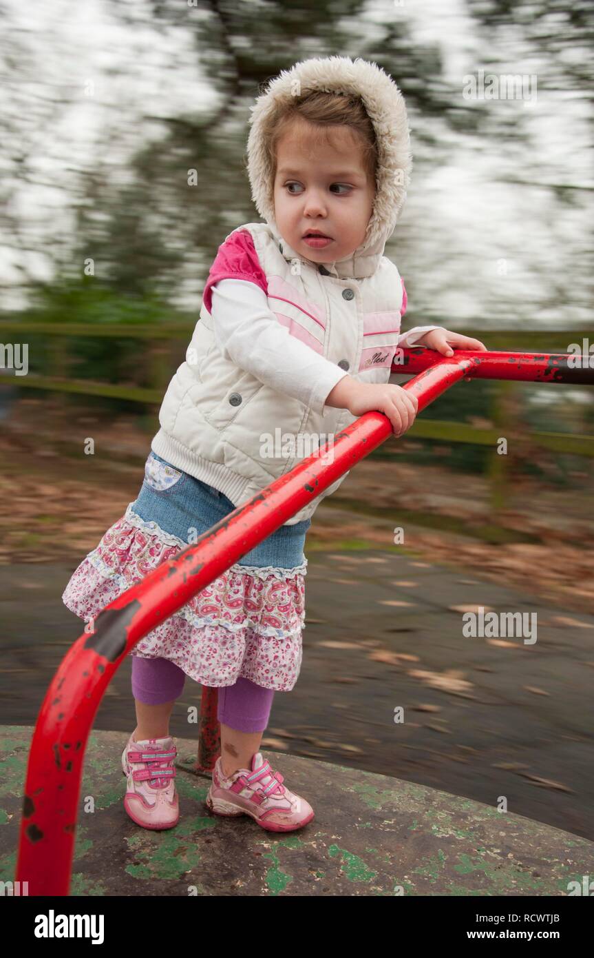 Junge Mädchen, drei Jahre, spielen auf dem Spielplatz Kreisverkehr Stockfoto