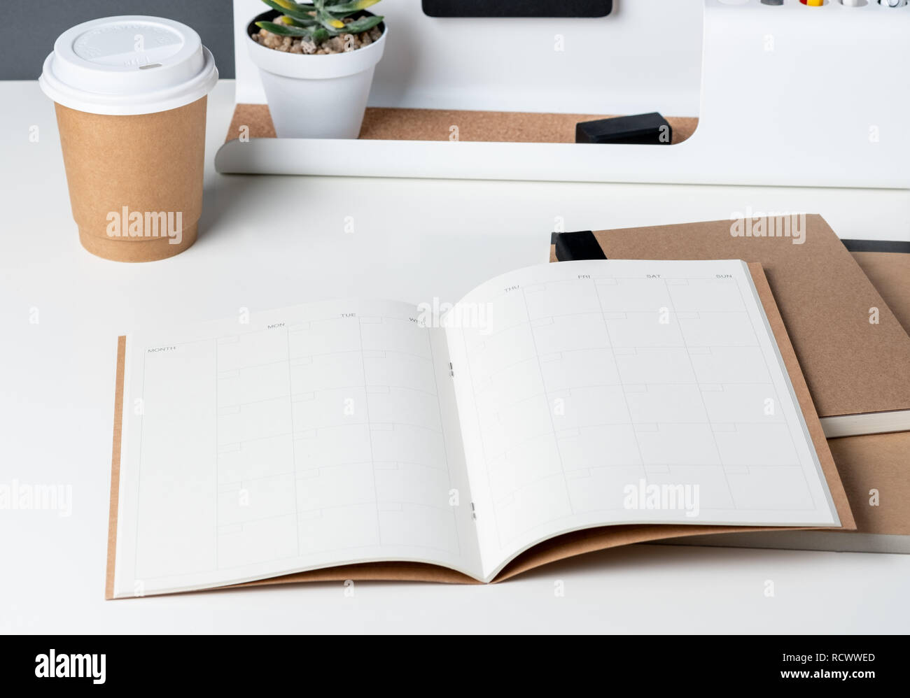 Ansicht von oben öffnen Sie Kalender Planer mit modernen Büro- und Schreibwaren, und nehmen Sie die Kaffeetasse auf weißem Schreibtisch im Büro. Mock up Raum des Veranstalters Tabelle beachten Stockfoto