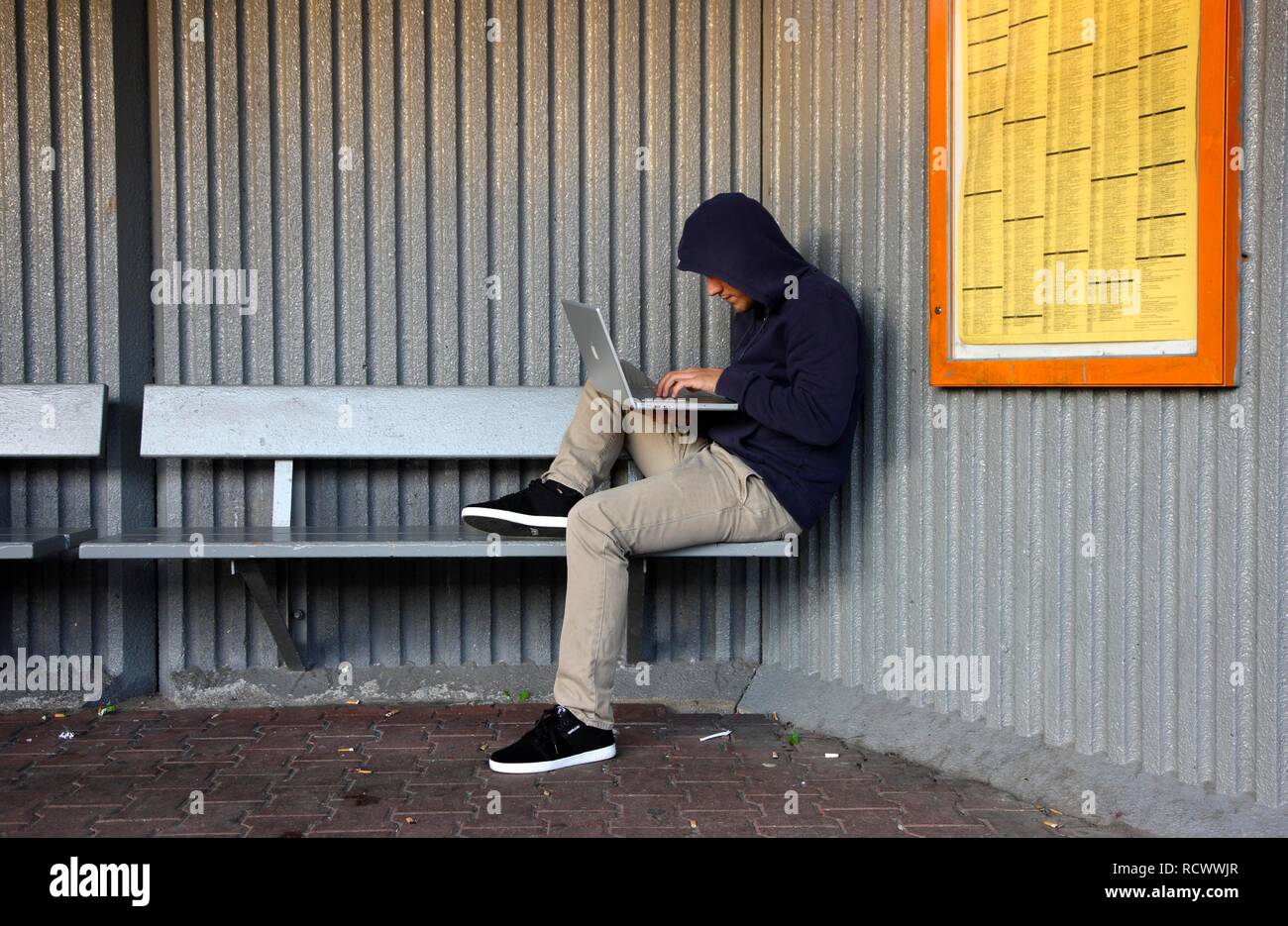 Man Surfen auf einem Laptop an einer Bushaltestelle, symbolische Bild für Hacking, Computer Kriminalität, Computerkriminalität, Datendiebstahl Stockfoto