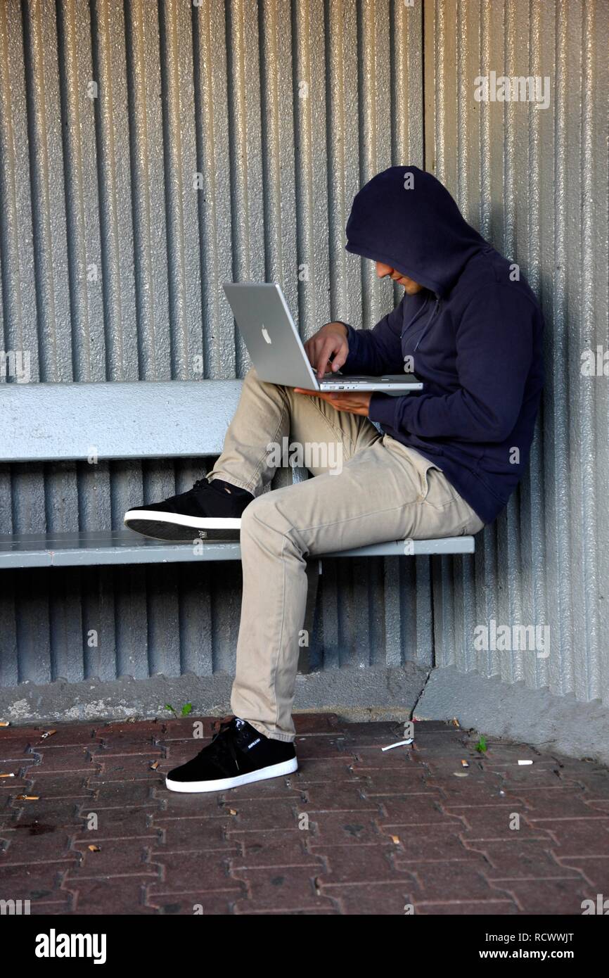 Man Surfen auf einem Laptop an einer Bushaltestelle, symbolische Bild für Hacking, Computer Kriminalität, Computerkriminalität, Datendiebstahl Stockfoto