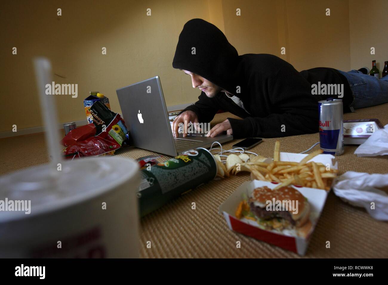 Hacker arbeitet an einem Laptop Computer in einem spärlich eingerichteten Wohnung, symbolische Bild für Hacking, Computerkriminalität Stockfoto