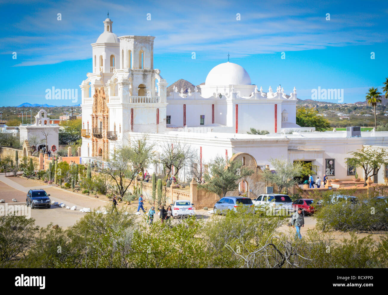 Leute durchstreifen das Gelände bei der historischen Mission San Xavier del Bac, einem Spanischen Katholischen Mission, in die Kakteen beladenen Wüste in der Nähe von Tucson, AZ gebaut Stockfoto