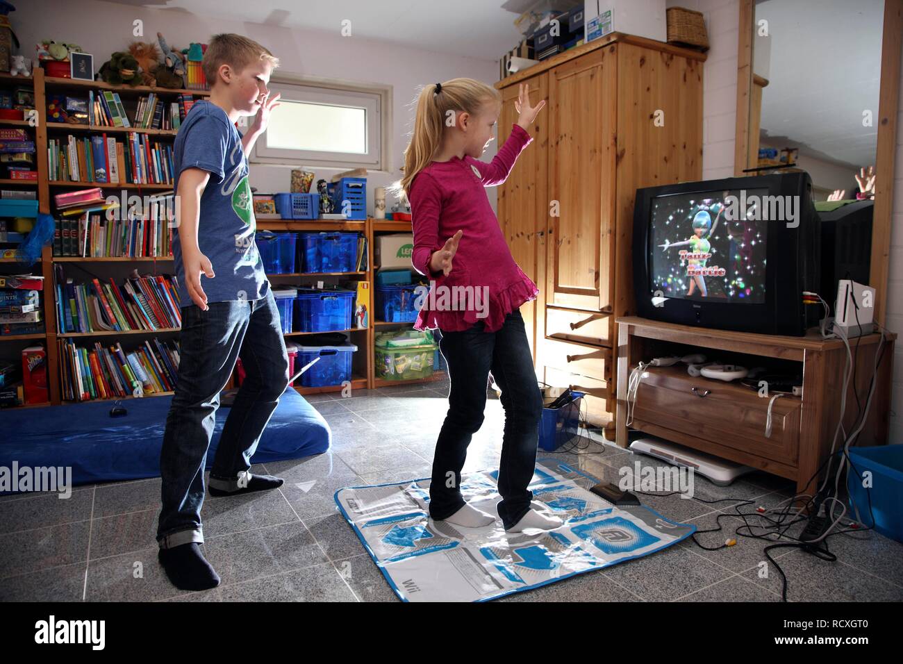 Geschwister, ein Junge, 12 Jahre alt, und ein Mädchen, 10 Jahre alt, spielen, Tanz Spiel auf Wii Spiele in Ihrem Zimmer Konsole zusammen Stockfoto