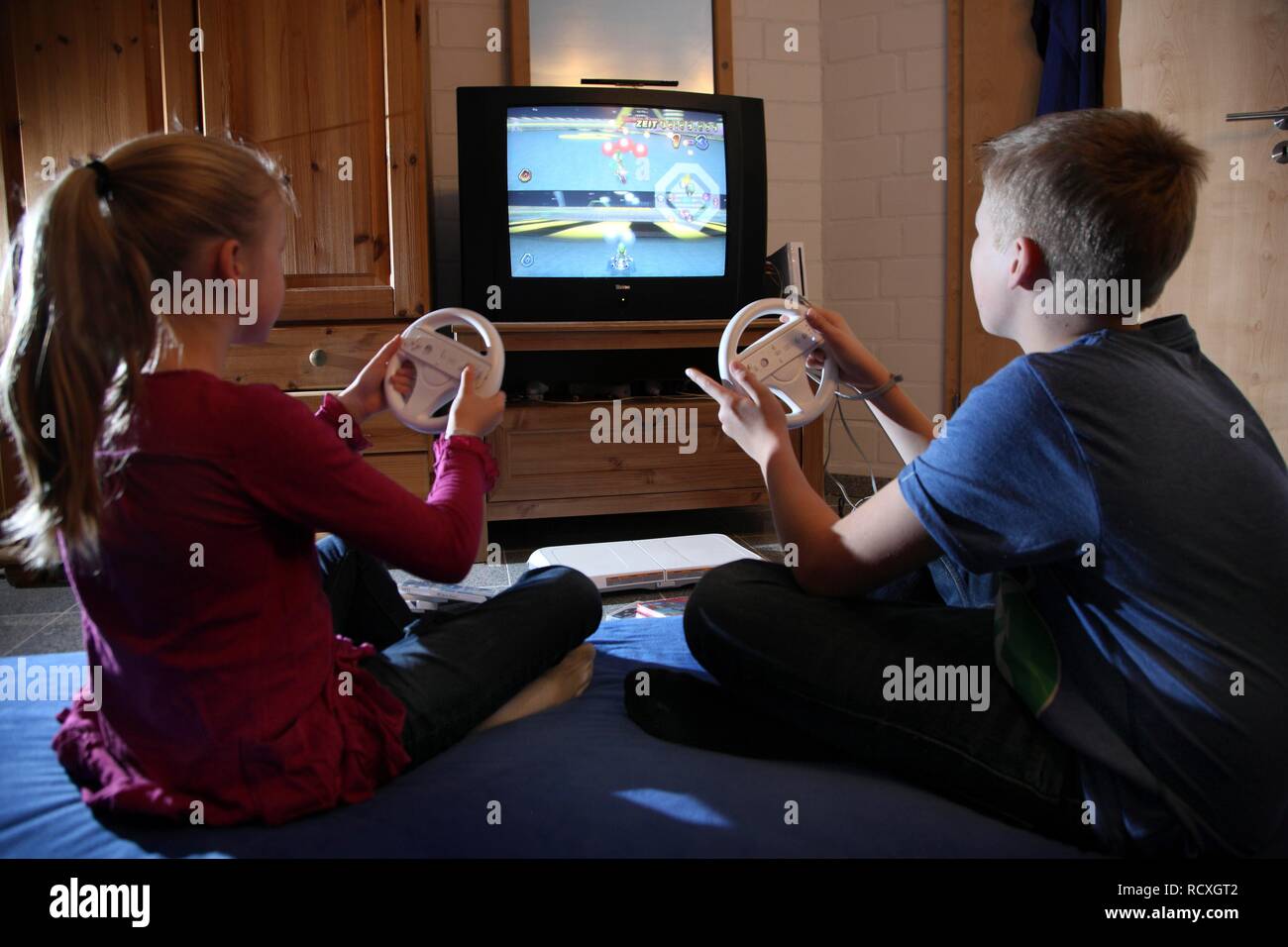 Geschwister, ein Junge, 12 Jahre alt, und ein Mädchen, 10 Jahre alt,  spielen ein Auto Rennspiel auf der Wii Spiele in Ihrem Zimmer Konsole  zusammen Stockfotografie - Alamy