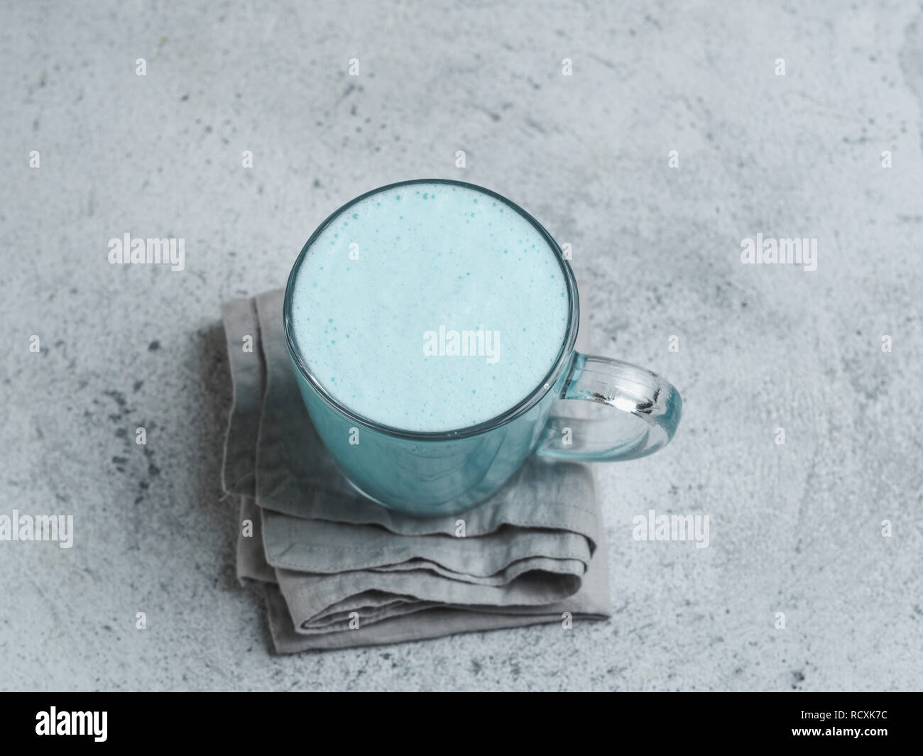 Trendgetränk: Blue latte. Blick von oben auf die heiße Butterfly pea Latte oder Blue spirulina Latte auf grauem Zement strukturierten Hintergrund. Kopieren Sie Platz für Text. Top View oder flach. Stockfoto