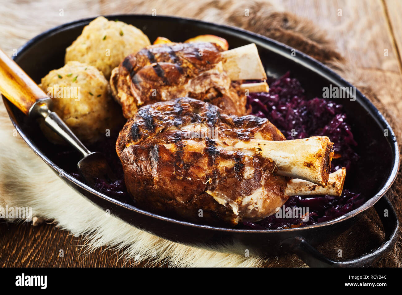Traditionelle deutsche gegrilltem Schweinefleisch Hock mit Klößen und Rotkohl auf einem winter Grill zubereitet und serviert in einer Pfanne Stockfoto