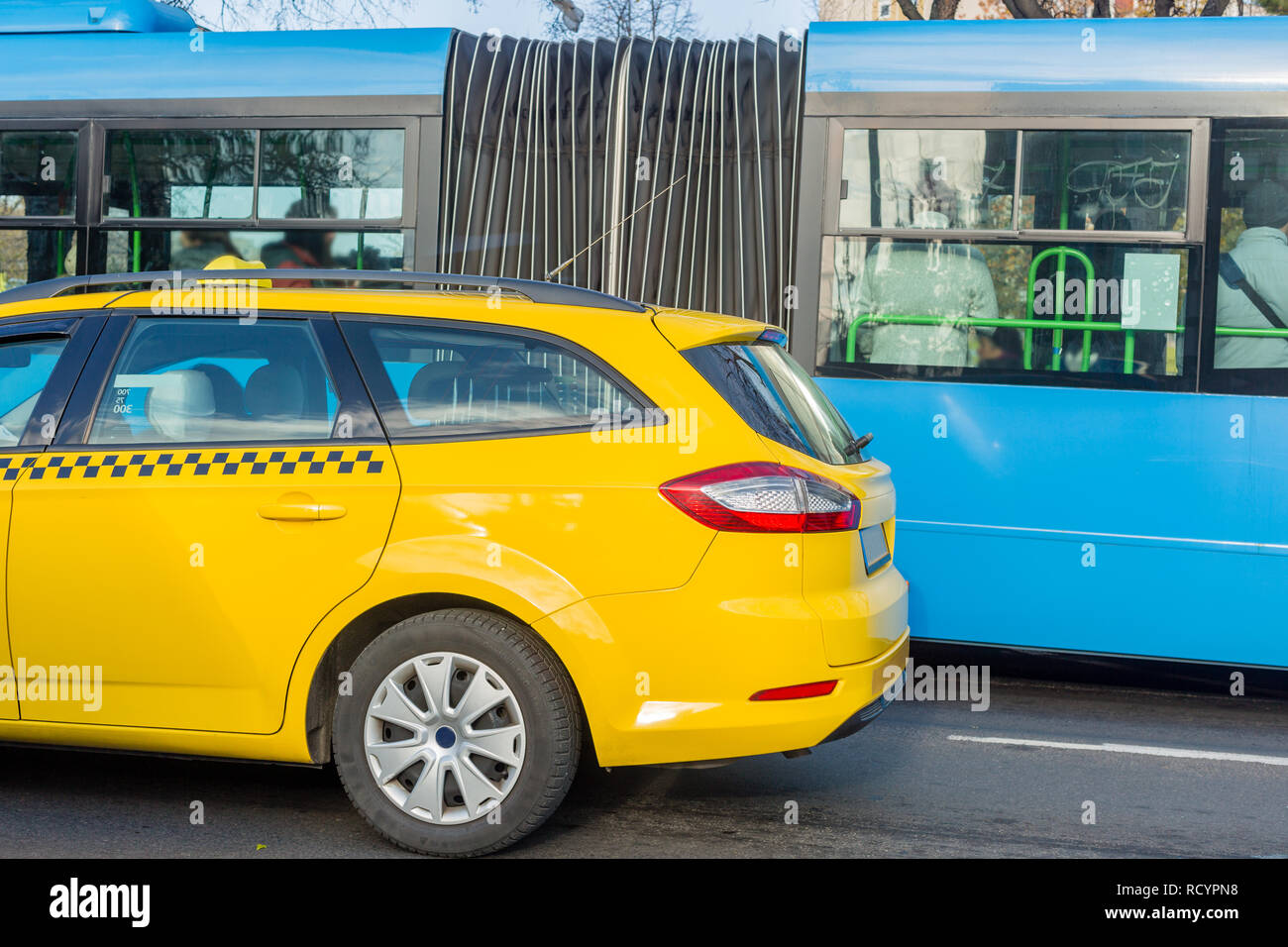 In der Nähe des gelben Taxi in der Nähe des blauen Bus. Mit dem Bus oder dem Taxi. City Transport und Auswahl des Fahrzeugs Konzept Stockfoto