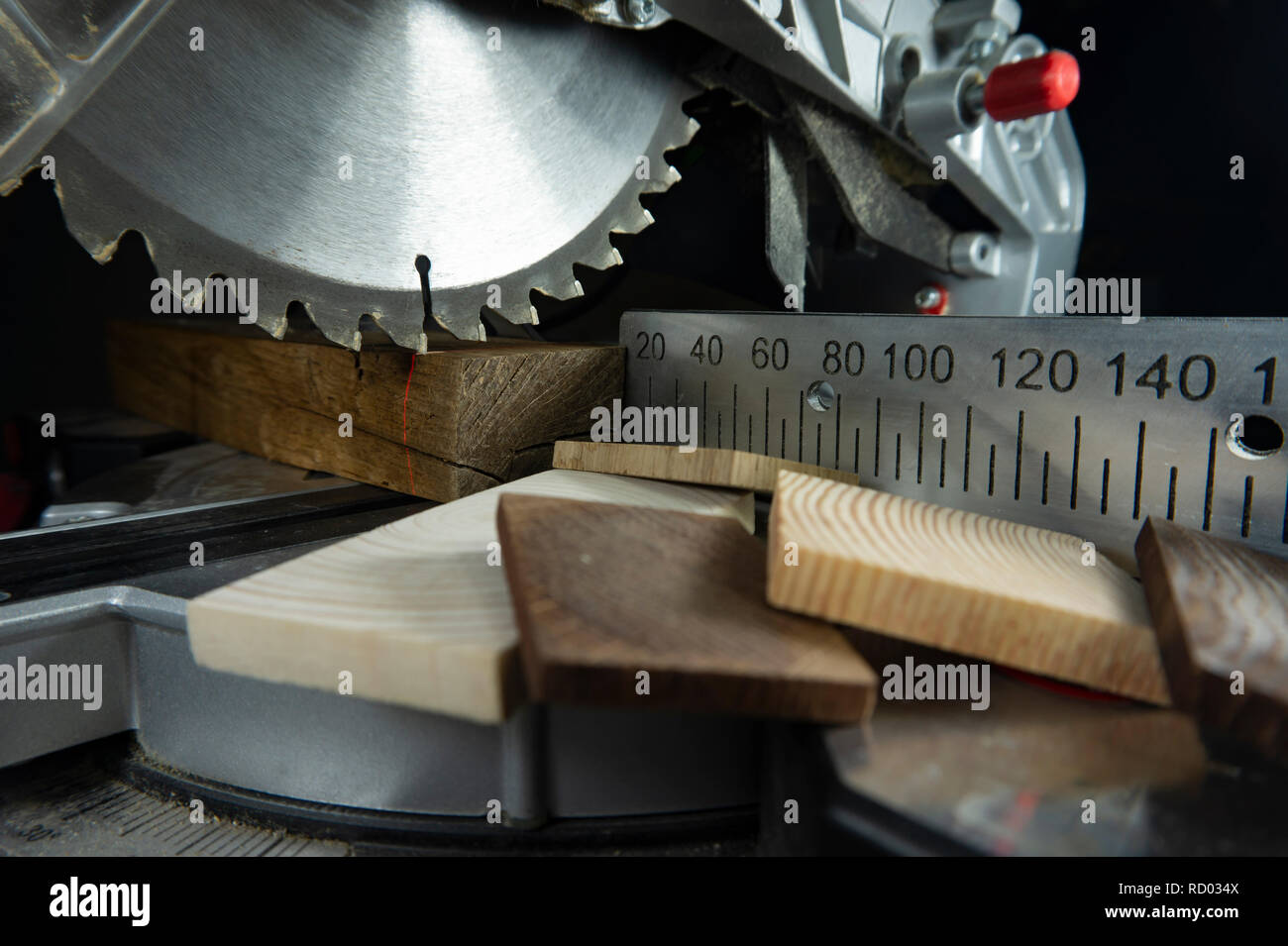 Zähne auf einer kreisförmigen Motorsäge in Nahaufnahme mit verschiedenen Bausteinen aus Holz und Metall Maßstab für Schnittlängen in einem Holzbearbeitung workshop Stockfoto