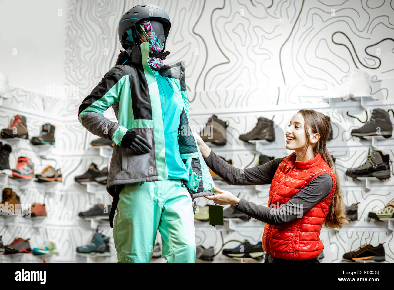 Glückliche Frau Wahl Skibekleidung Suche auf dem Dummy an der luxuriösen Sports Shop Stockfoto